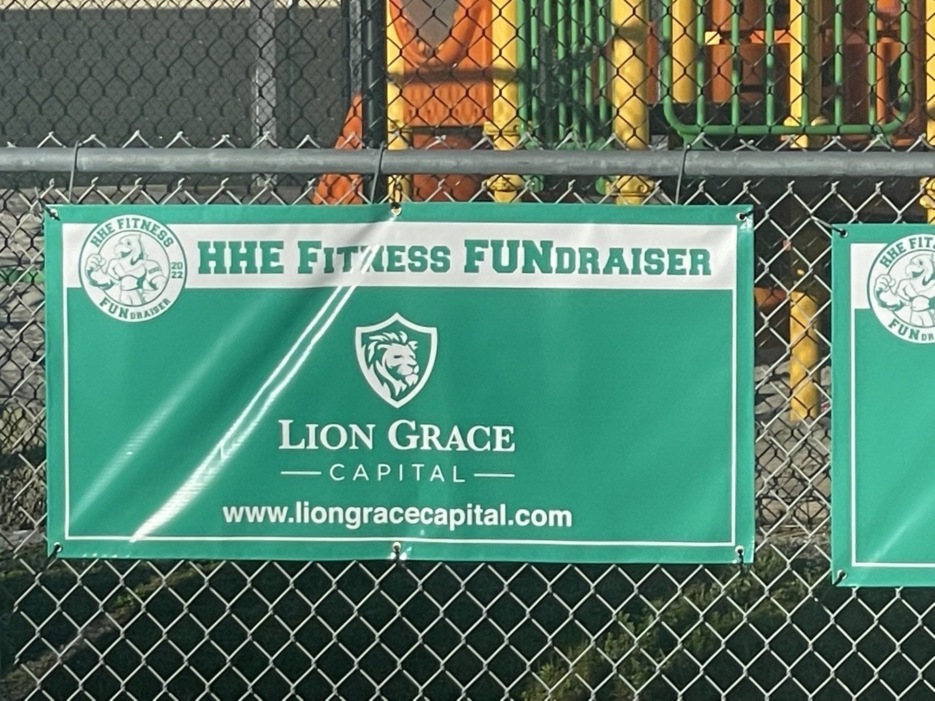 A lion grace capital sign hangs on a chain link fence