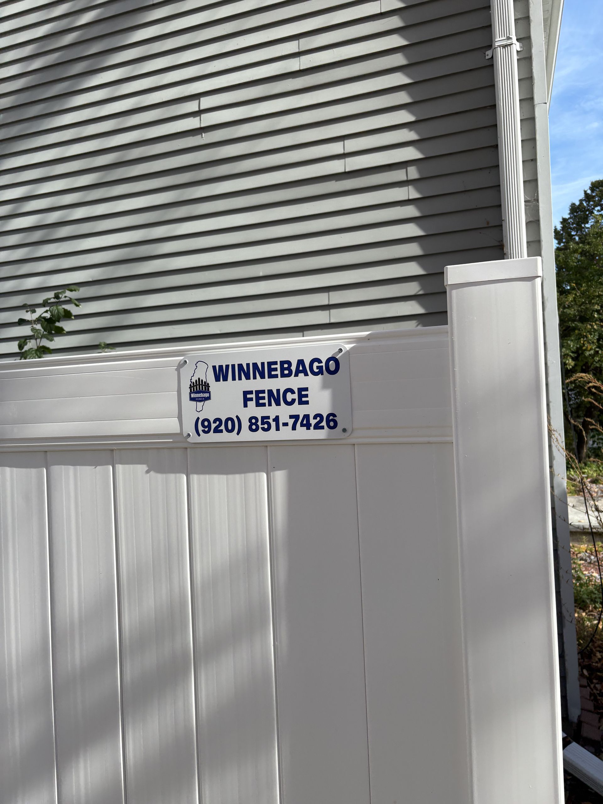 White vinyl fence with a sign that reads 