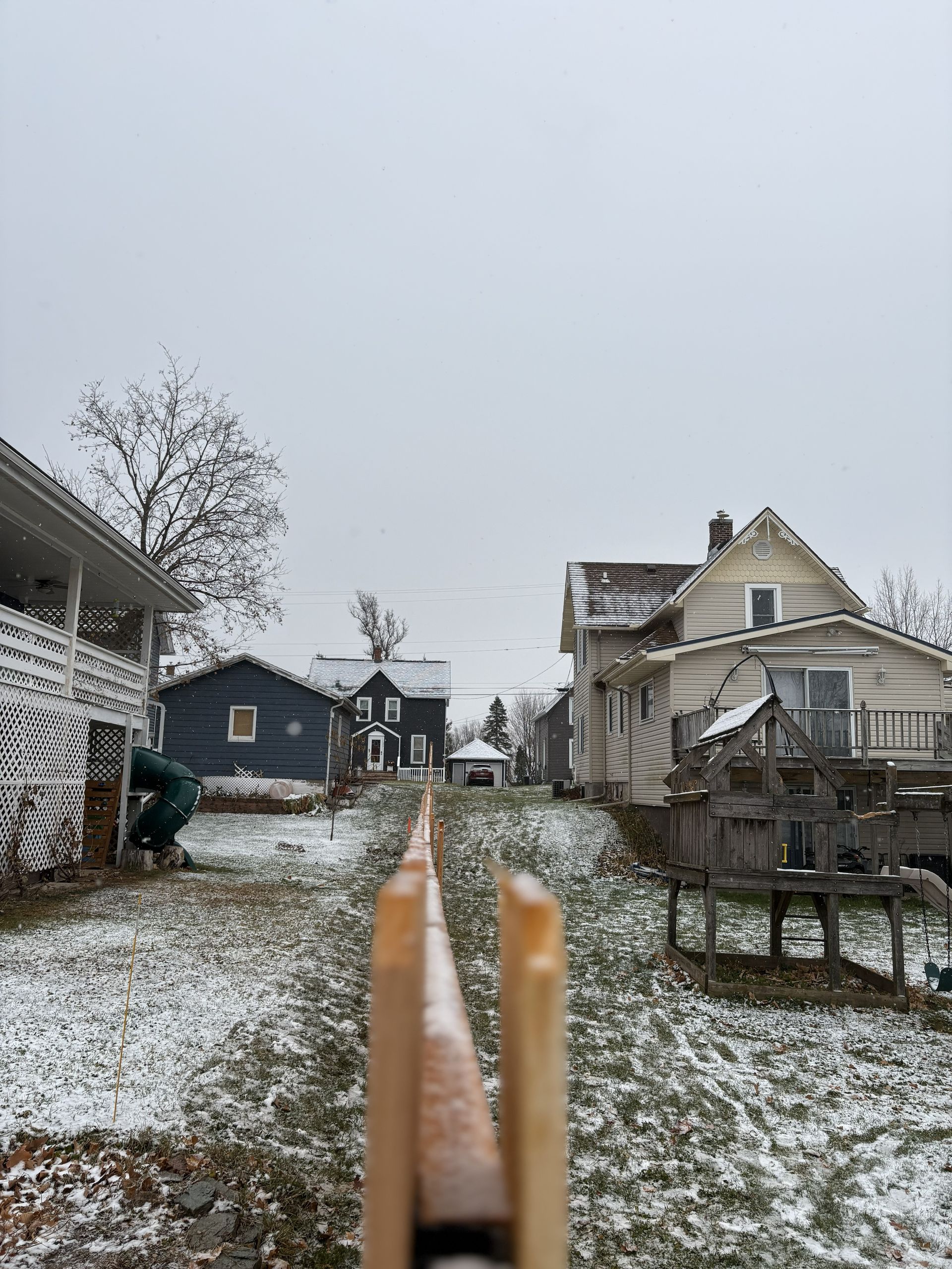 A snowy backyard with a clothesline in focus; houses and a gray sky in the background.