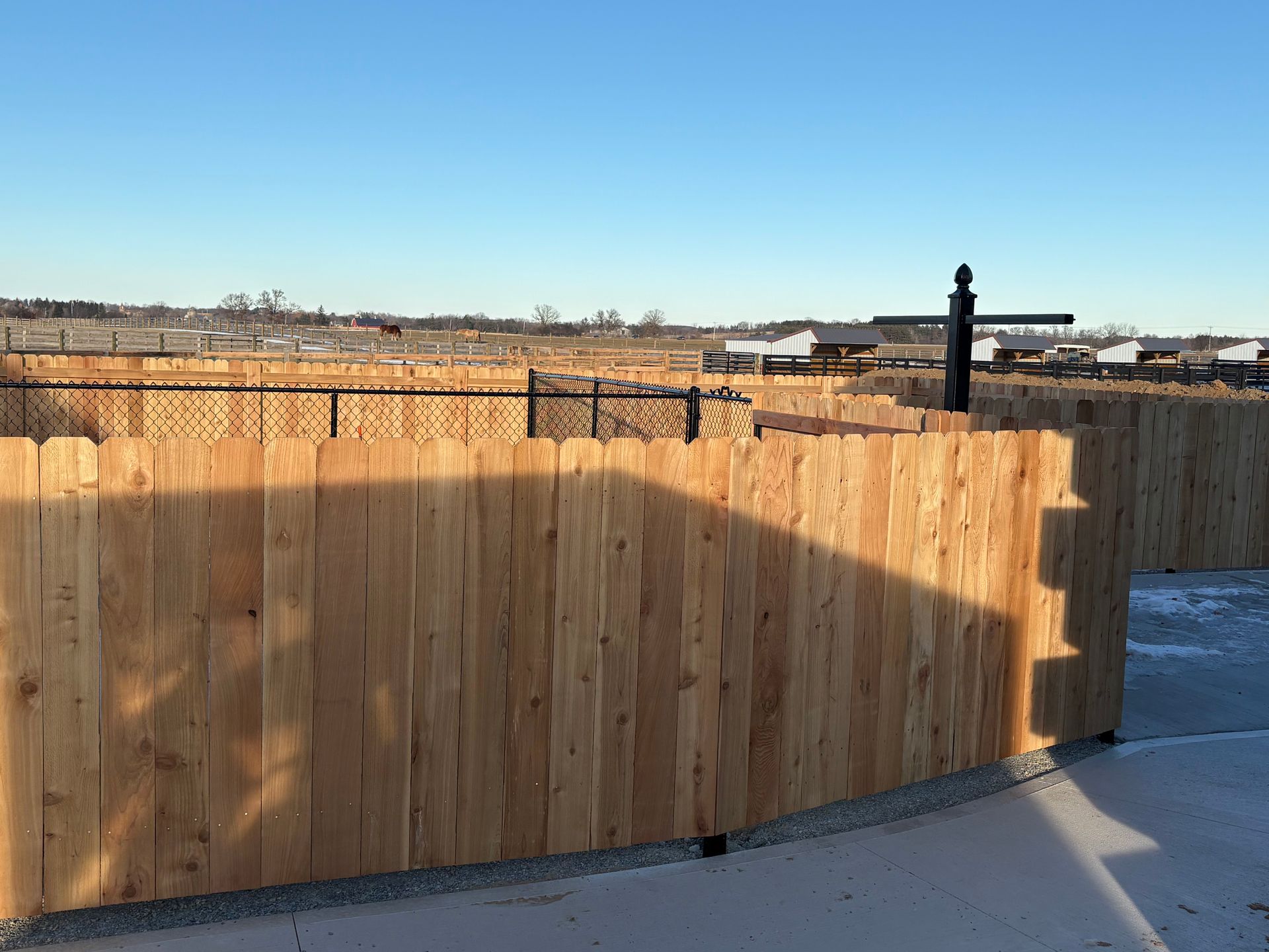 Wooden fence with black chain link in the background under a blue sky.