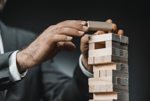 Man in suit placing wooden block on tower.