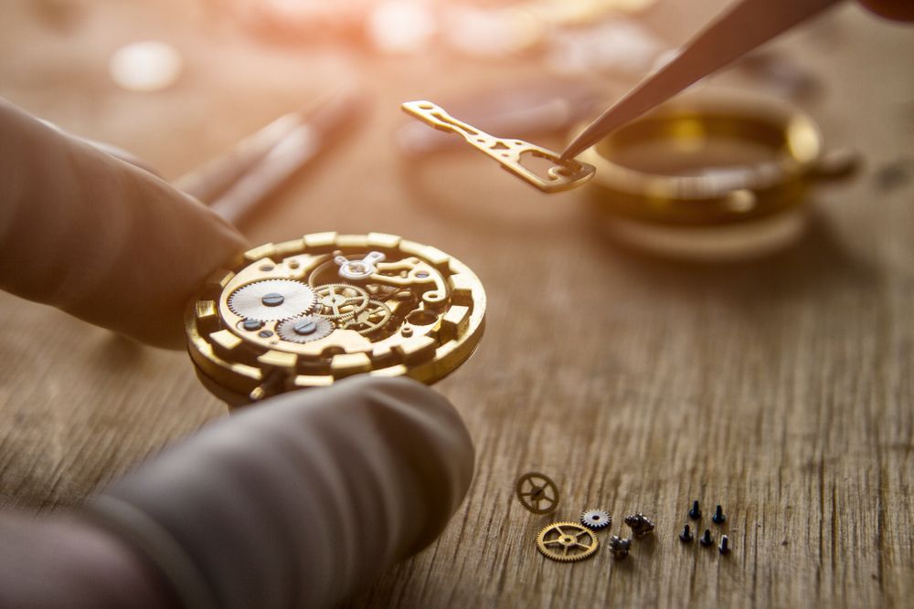 A Person is Working on a Watch on a Wooden Table — K. Smith & Son Jewellers In Caloundra, QLD