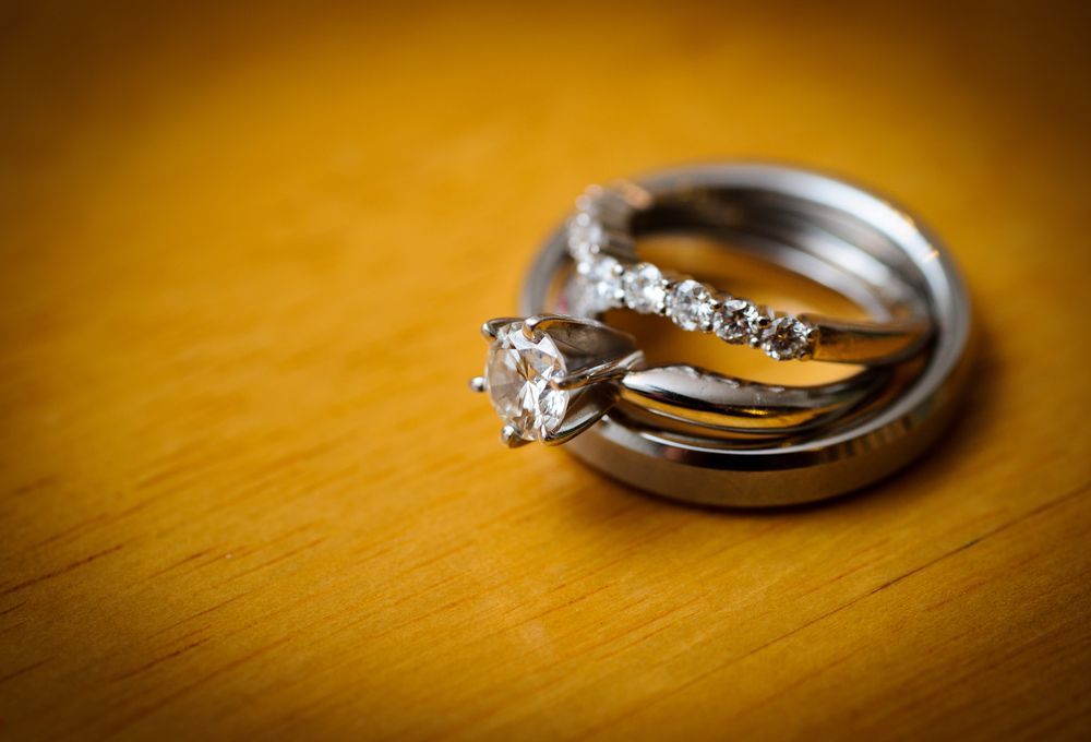 A Close Up of a Wedding Ring and Engagement Ring on a Wooden Table — K. Smith & Son Jewellers In Caloundra, QLD