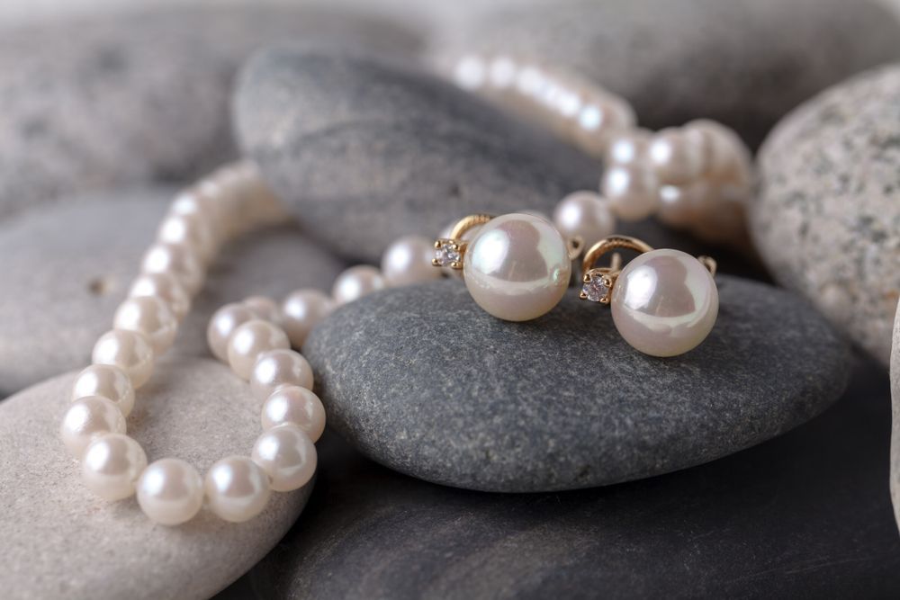 A Pearl Necklace and Earrings Are Sitting on a Pile of Rocks — K. Smith & Son Jewellers In Caloundra, QLD