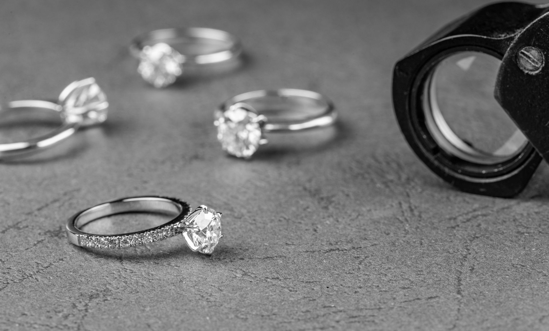A Group of Rings Are Sitting on a Table Next to a Magnifying Glass — K. Smith & Son Jewellers In Caloundra, QLD