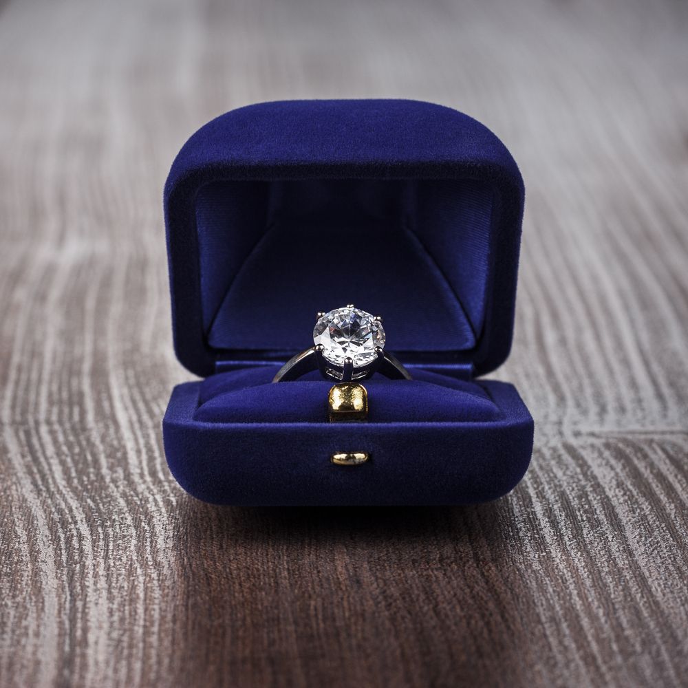 A Diamond Ring in a Blue Box on a Wooden Table — K. Smith & Son Jewellers In Caloundra, QLD