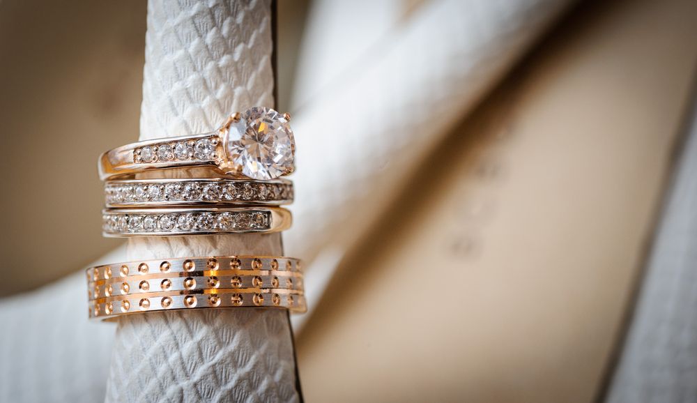 Close-up of Four Wedding Rings Stacked on a White Leather Strap — K. Smith & Son Jewellers In Caloundra, QLD