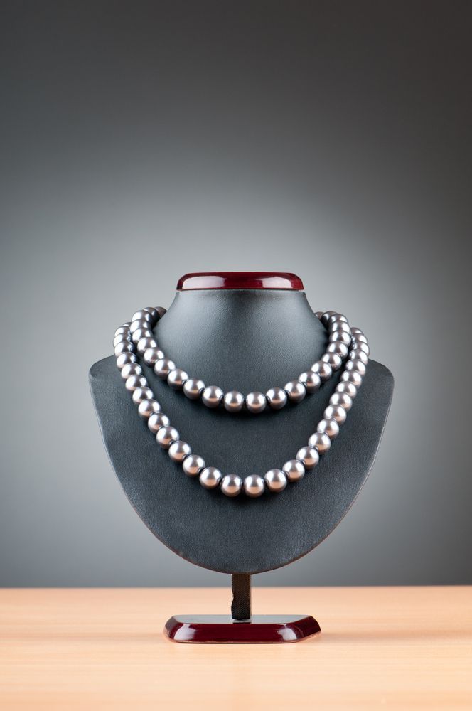 A Pearl Necklace is on a Mannequin on a Wooden Table — K. Smith & Son Jewellers In Caloundra, QLD