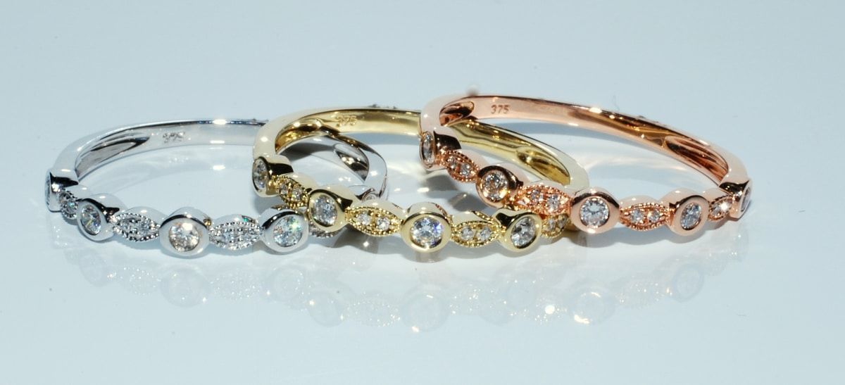Three Diamond Rings in White Gold, Yellow Gold, and Rose Gold Are on A Light Surface — K. Smith & Son Jewellers In Caloundra, QLD