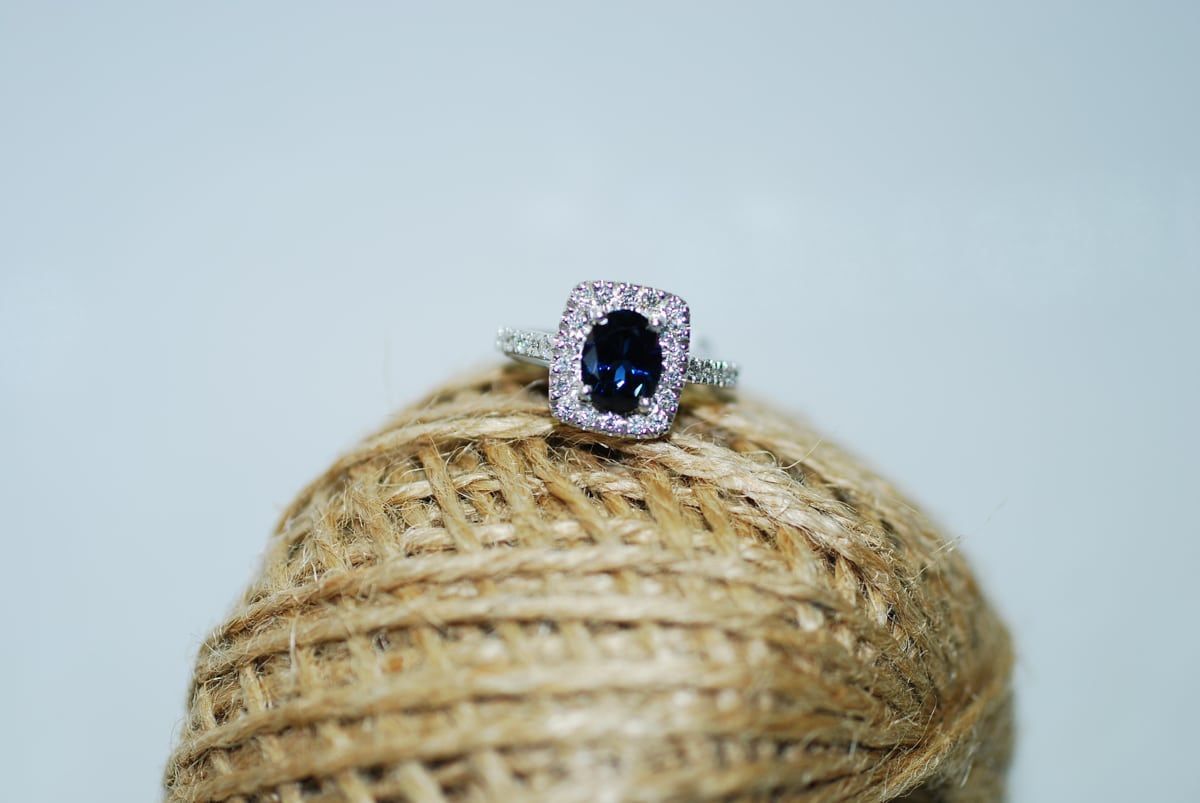 A Sapphire Ring with A Halo of Small Diamonds Rests on A Ball of Brown Twine — K. Smith & Son Jewellers In Caloundra, QLD