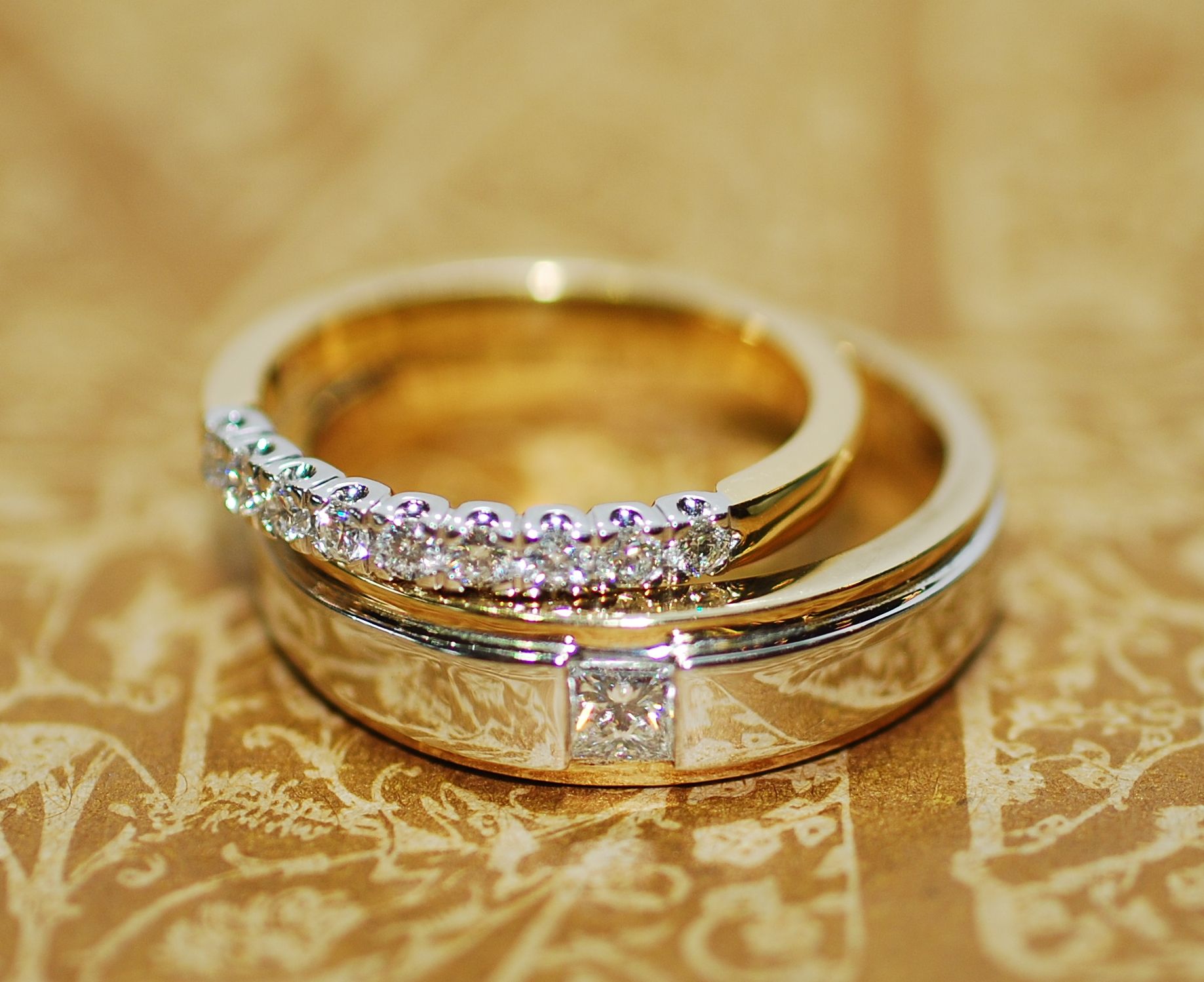 Wedding rings, one gold with diamonds, stacked on a wider gold band with a square diamond — K. Smith & Son Jewellers In Caloundra, QLD