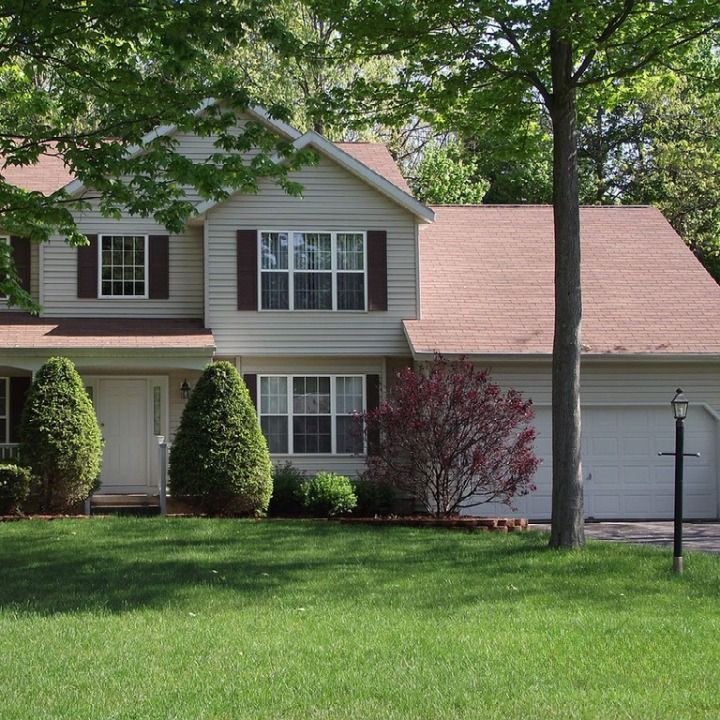 A white house with a red roof and brown shutters