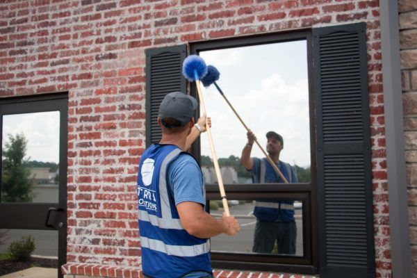 A man in a blue vest is cleaning a window