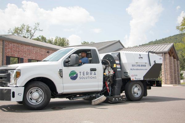 A white truck with terra solutions written on the side is parked in front of a building.