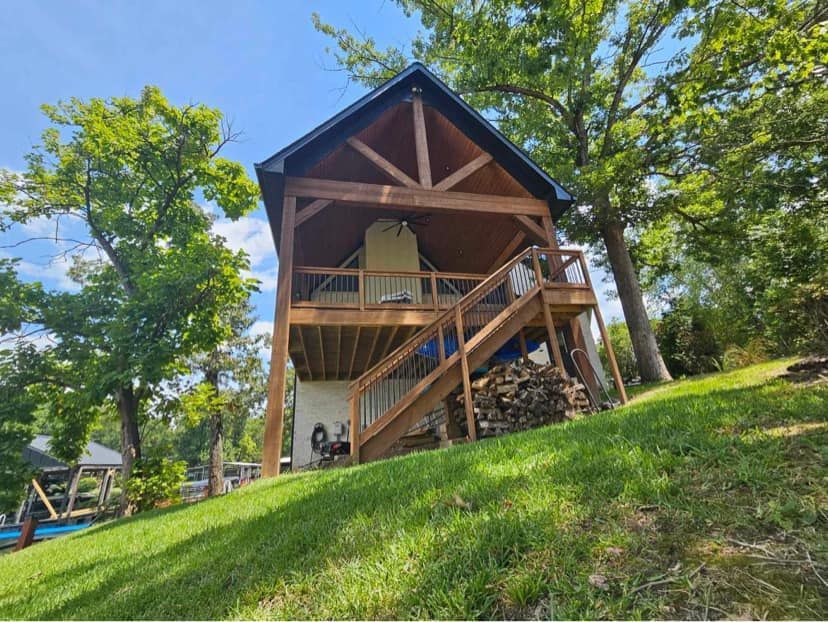 A small house is sitting on top of a grassy hill surrounded by trees.