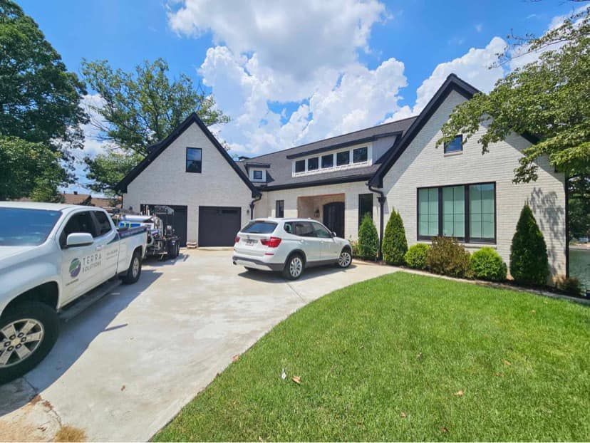 A white truck is parked in front of a large white house.