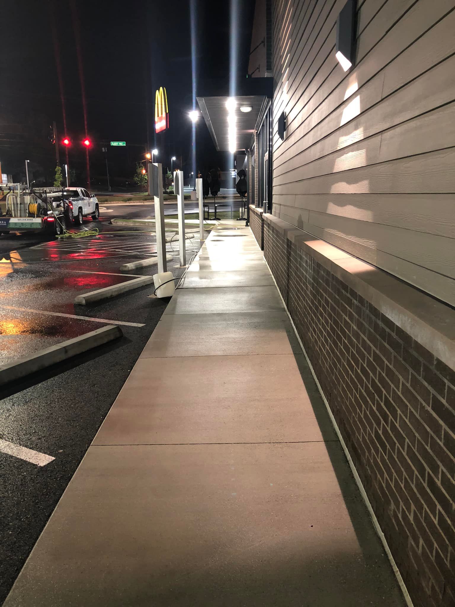 A sidewalk leading to a mcdonald 's restaurant at night