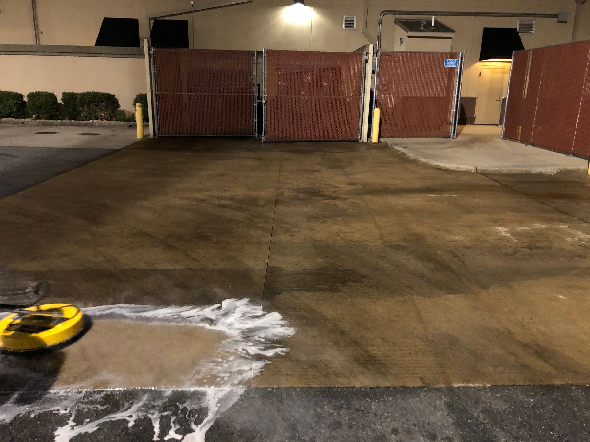 A person is using a pressure washer to clean a parking lot.