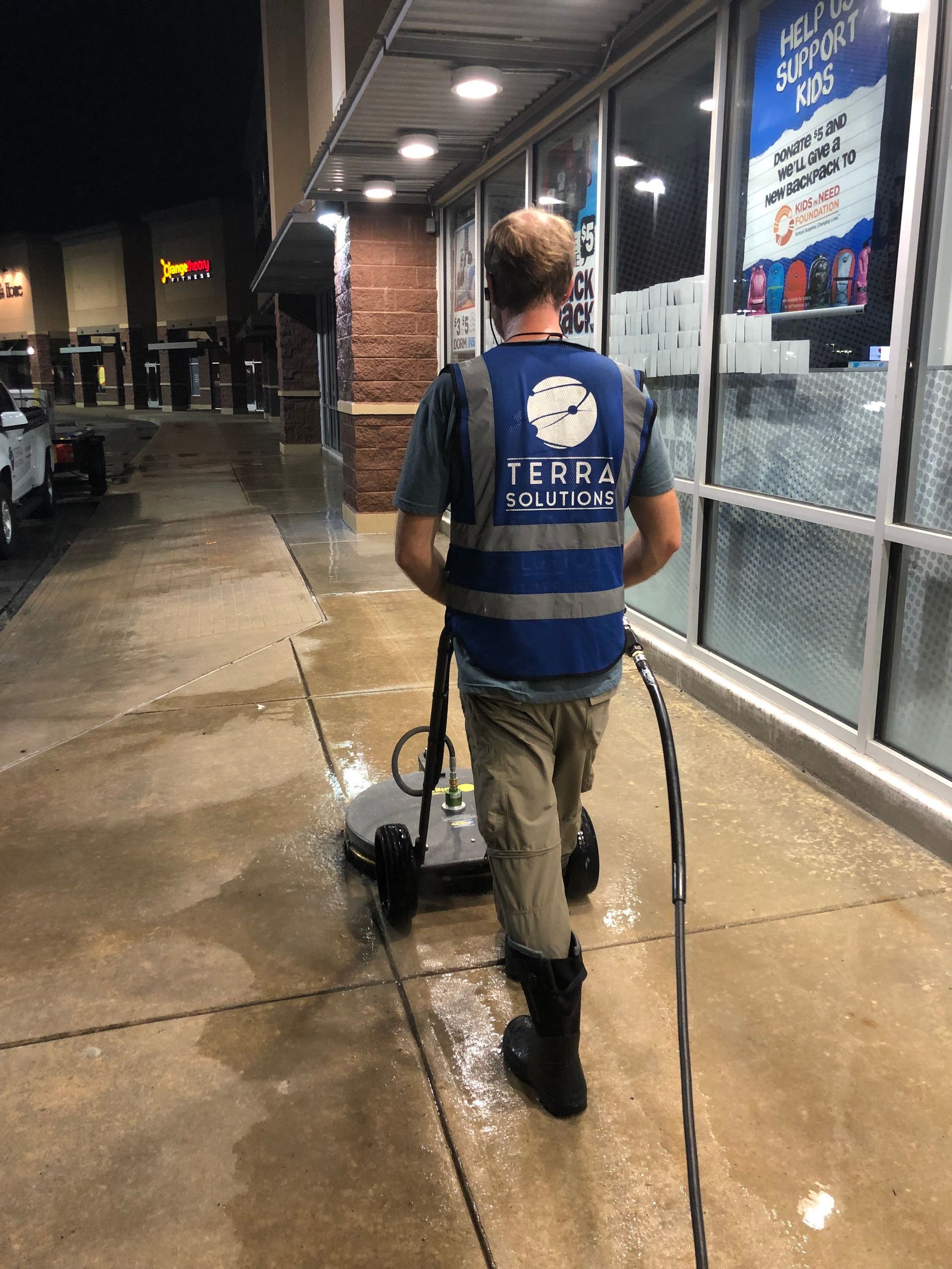 A man is cleaning a sidewalk with a machine.