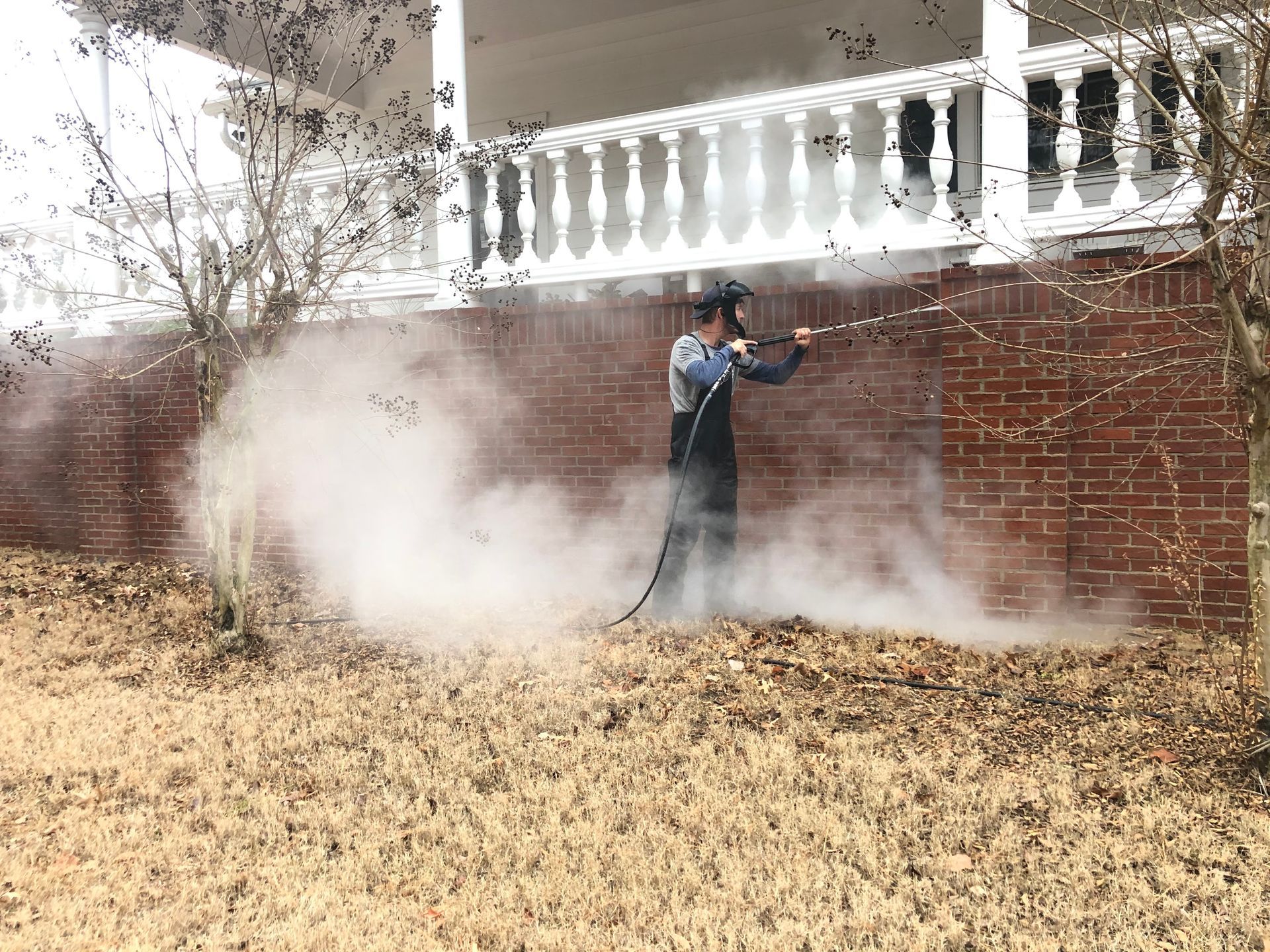 A man is cleaning a brick wall with a high pressure washer.