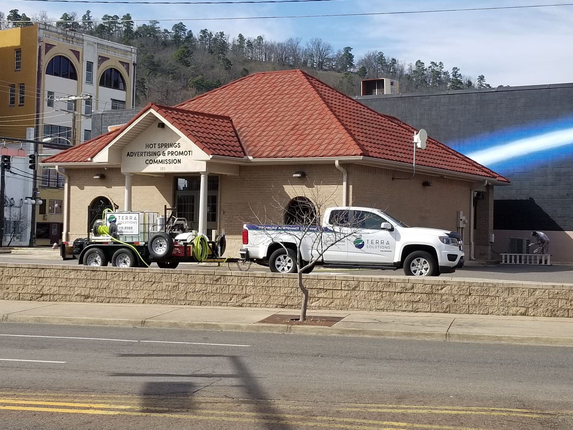Two trucks are parked in front of a building with a red roof.