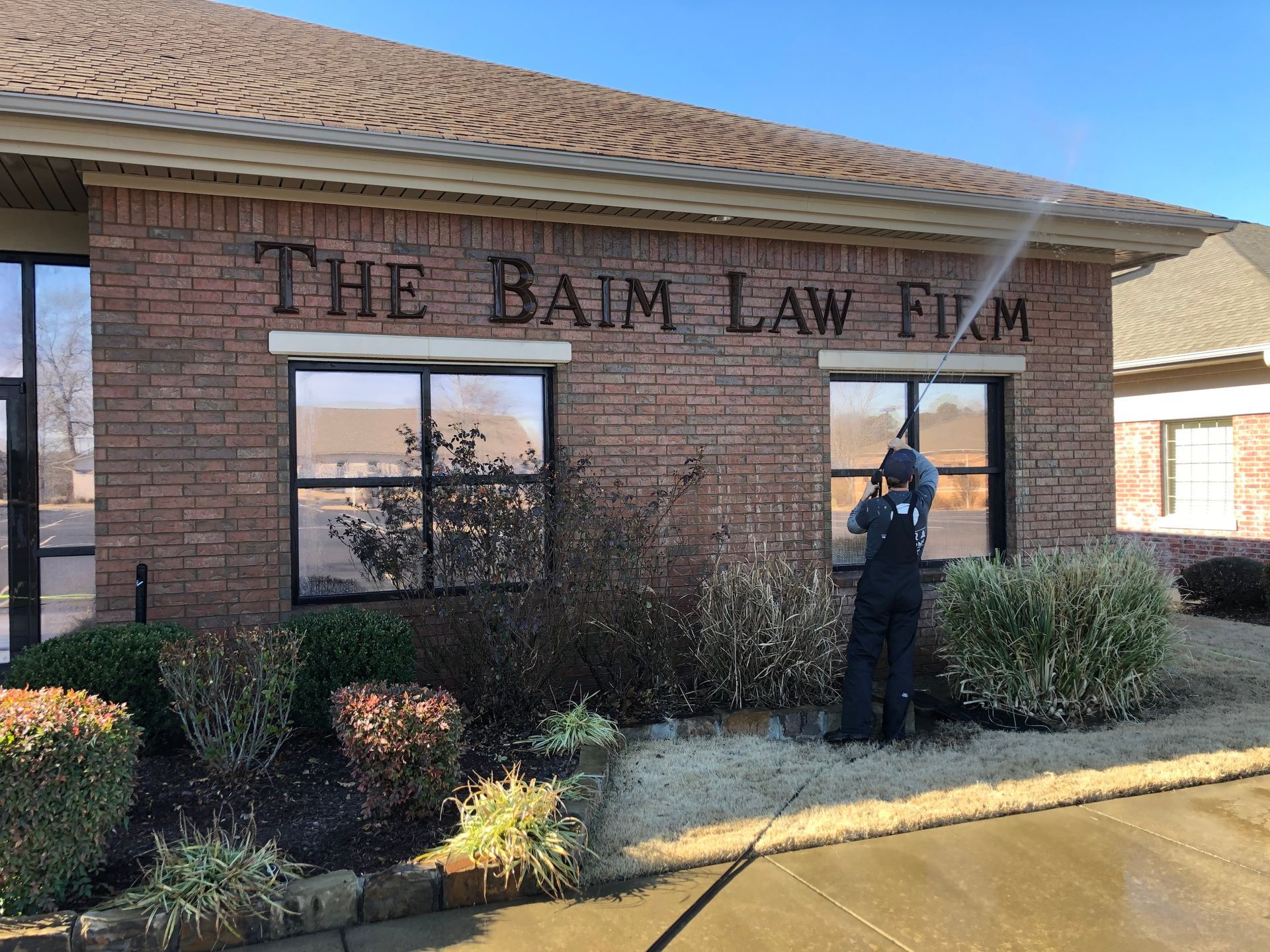 A man is cleaning the windows of a brick building.