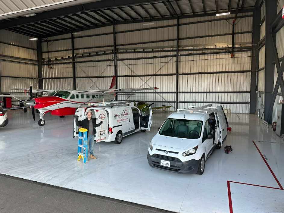 A man is standing next to a van in a hangar.