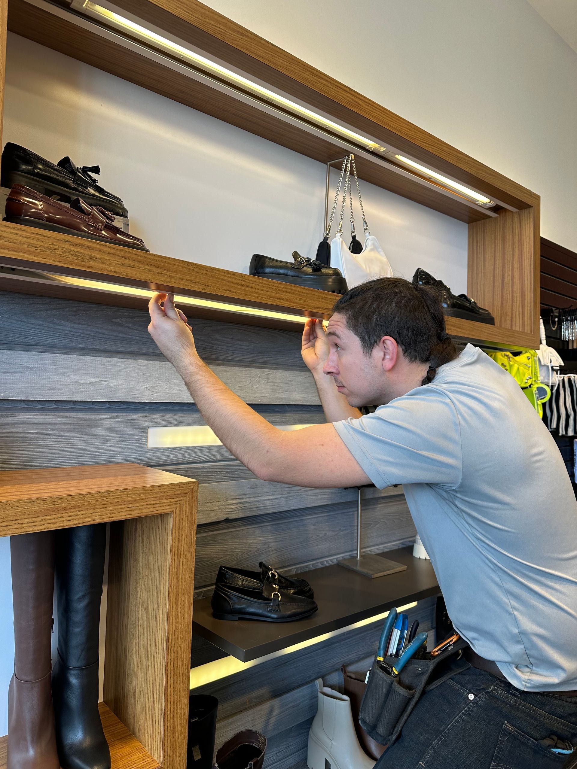 A man is working on a shelf in a store.