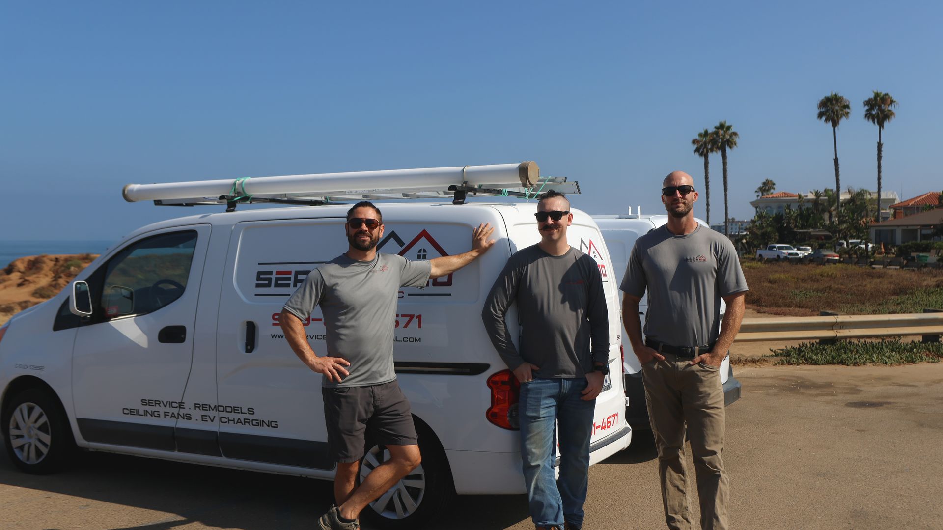 Three men are standing in front of a white van.