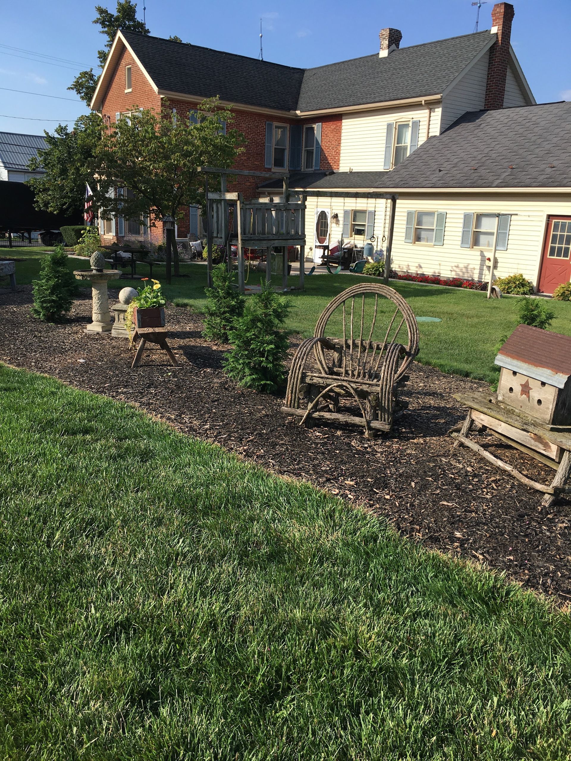 Farmhouse with garden, wooden decorations, and green lawn.