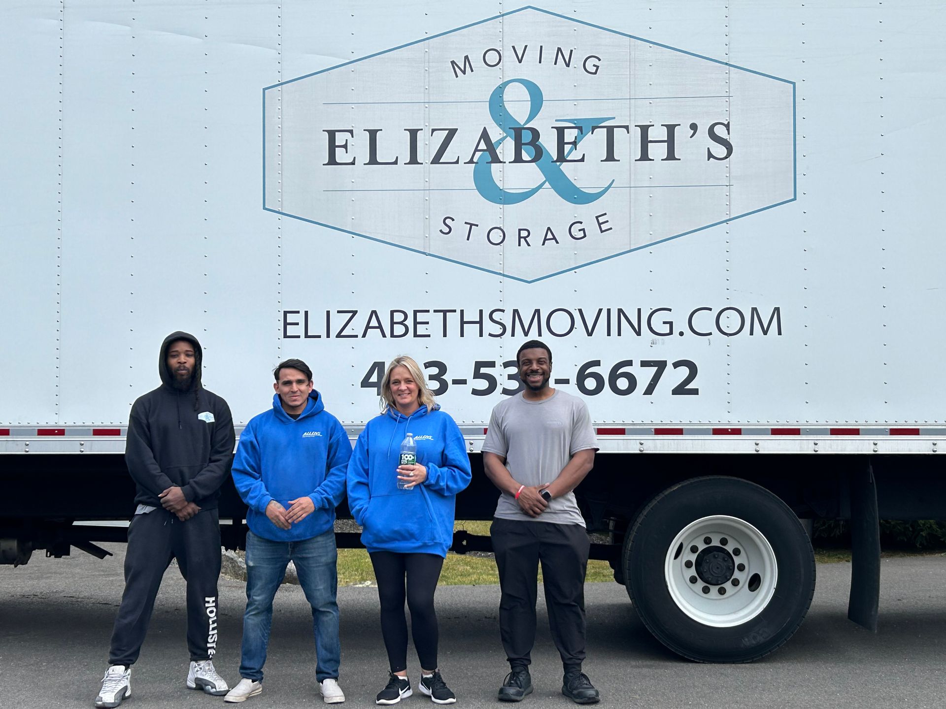 A group of people standing in front of a moving truck.