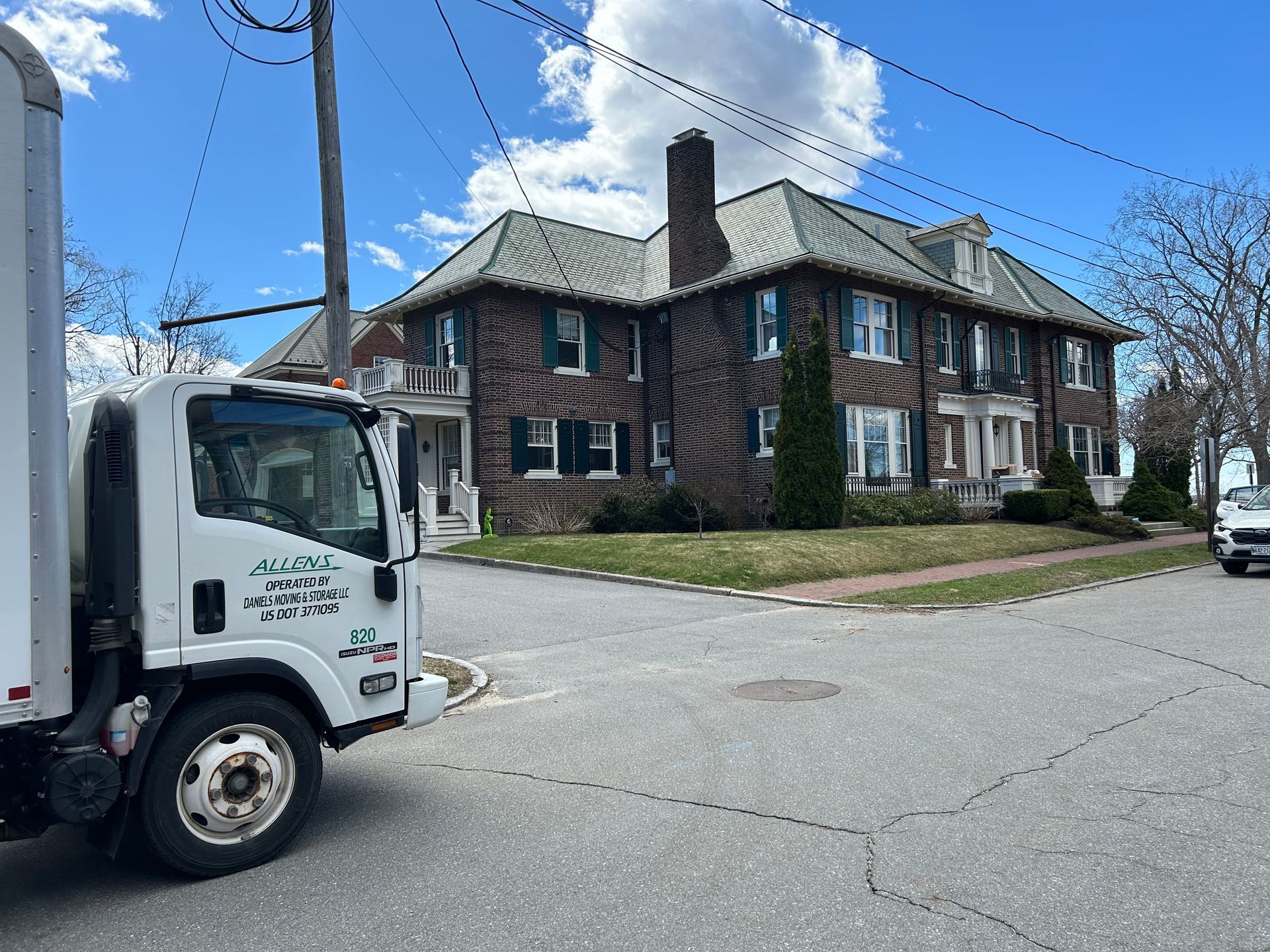 A white truck is parked in front of a large brick house.