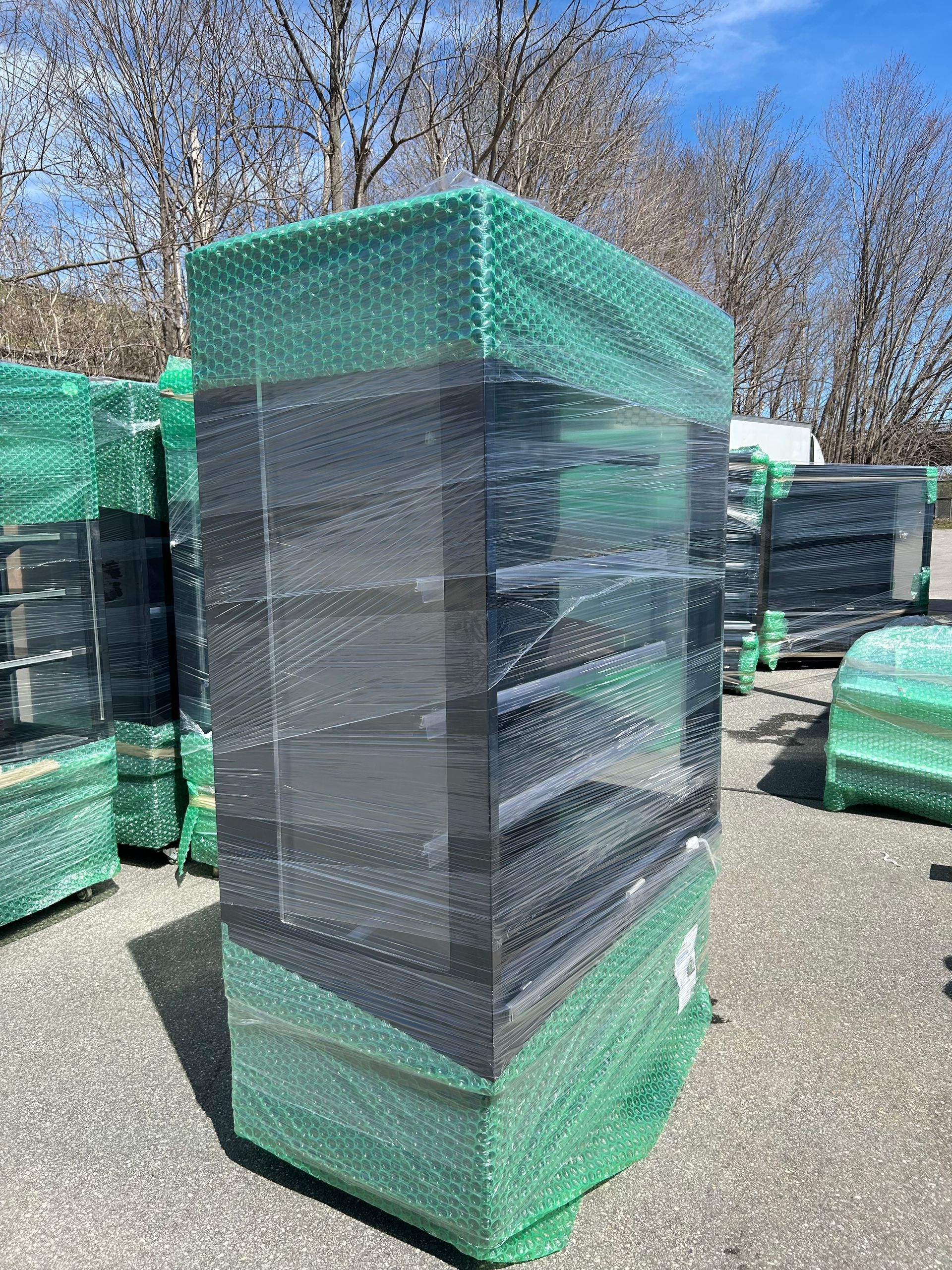 A large item wrapped in green plastic is sitting on the ground.