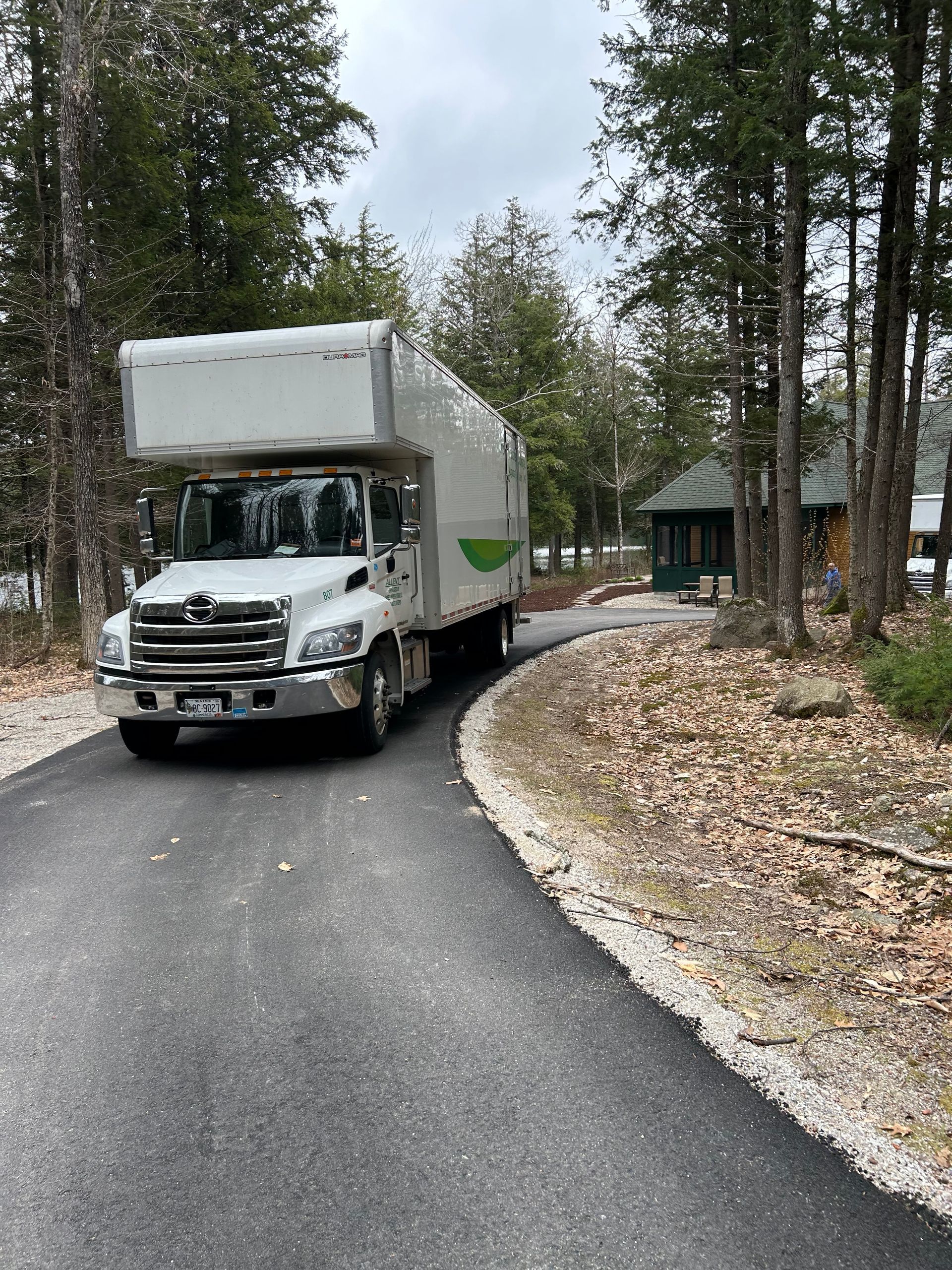 A white moving truck is driving down a curvy road.