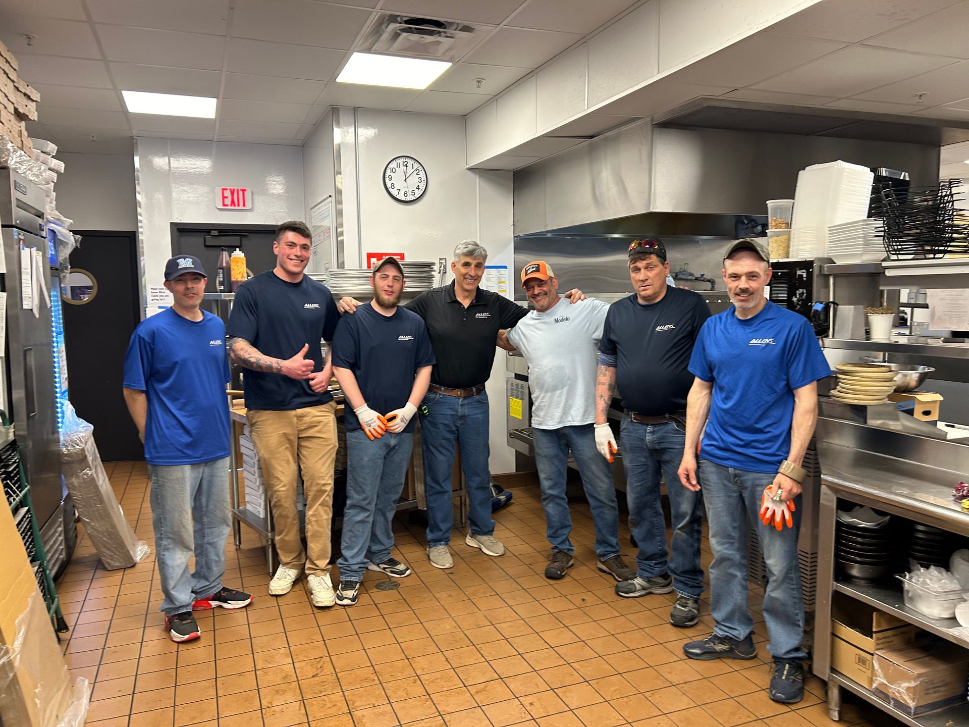 A group of men are posing for a picture in a kitchen.