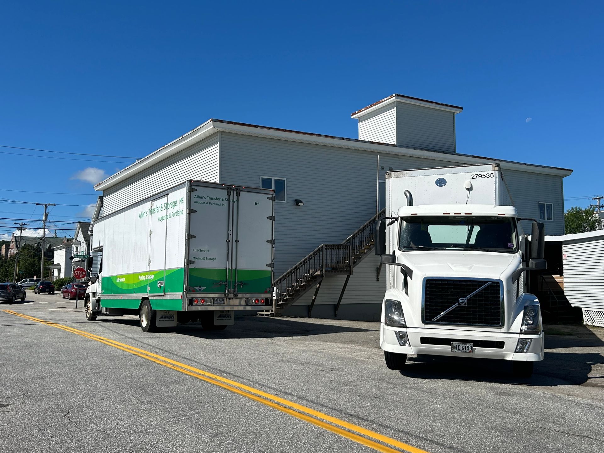 Two moving trucks are parked in front of a building.