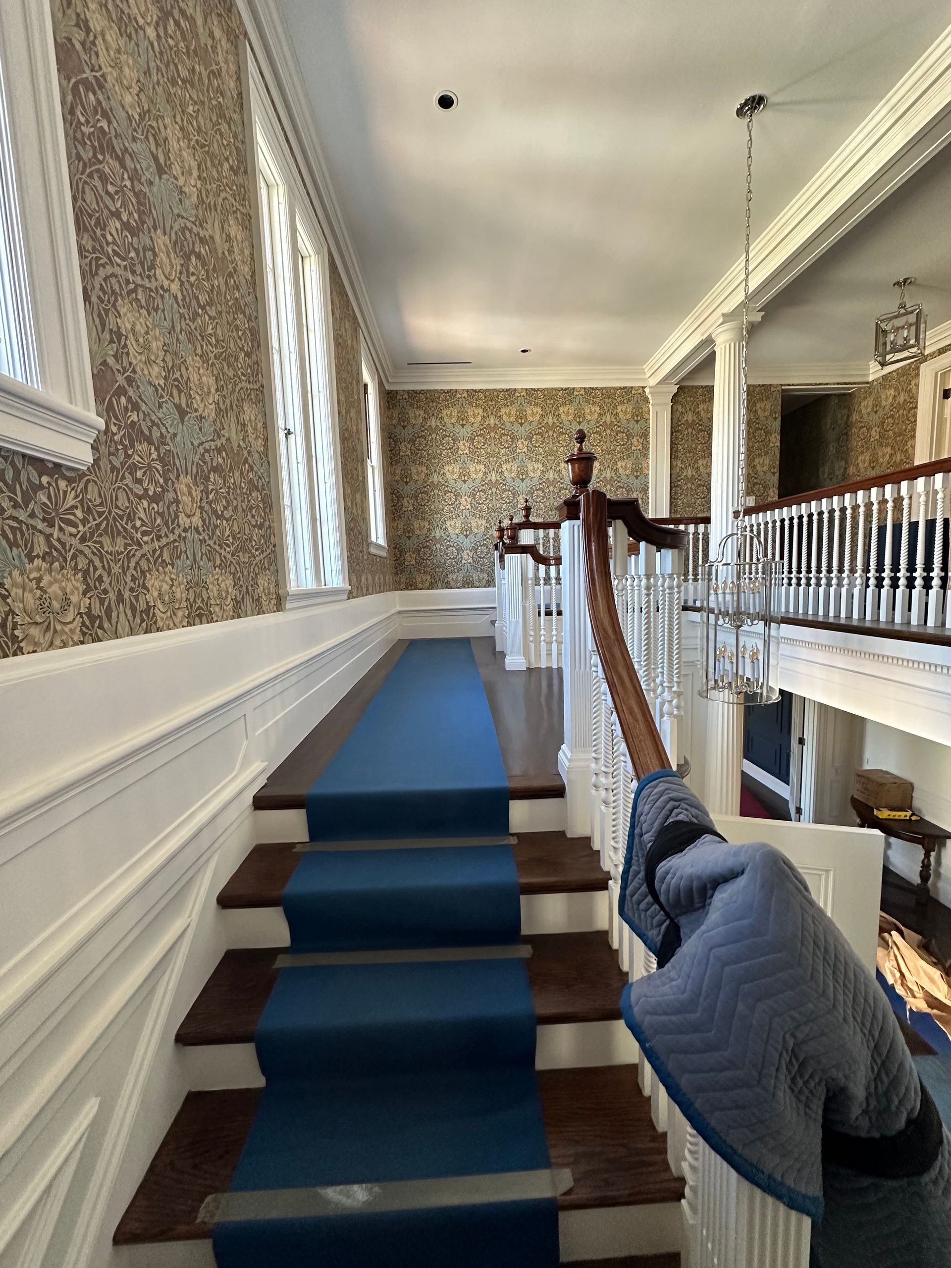 A person is standing on a set of stairs with a blue carpet.