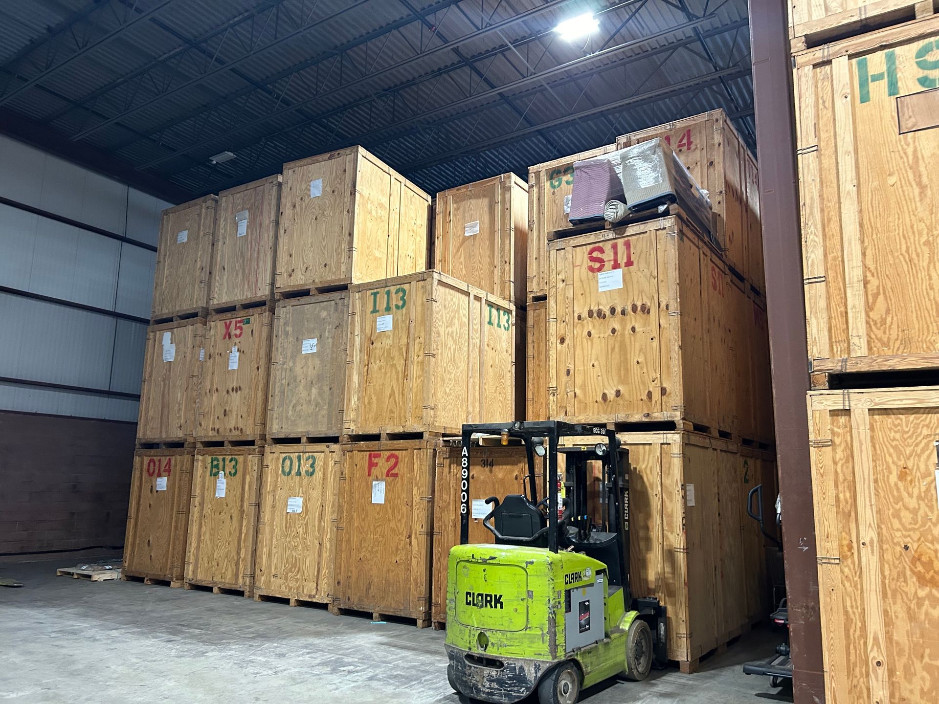 A forklift is driving through a warehouse filled with wooden crates.