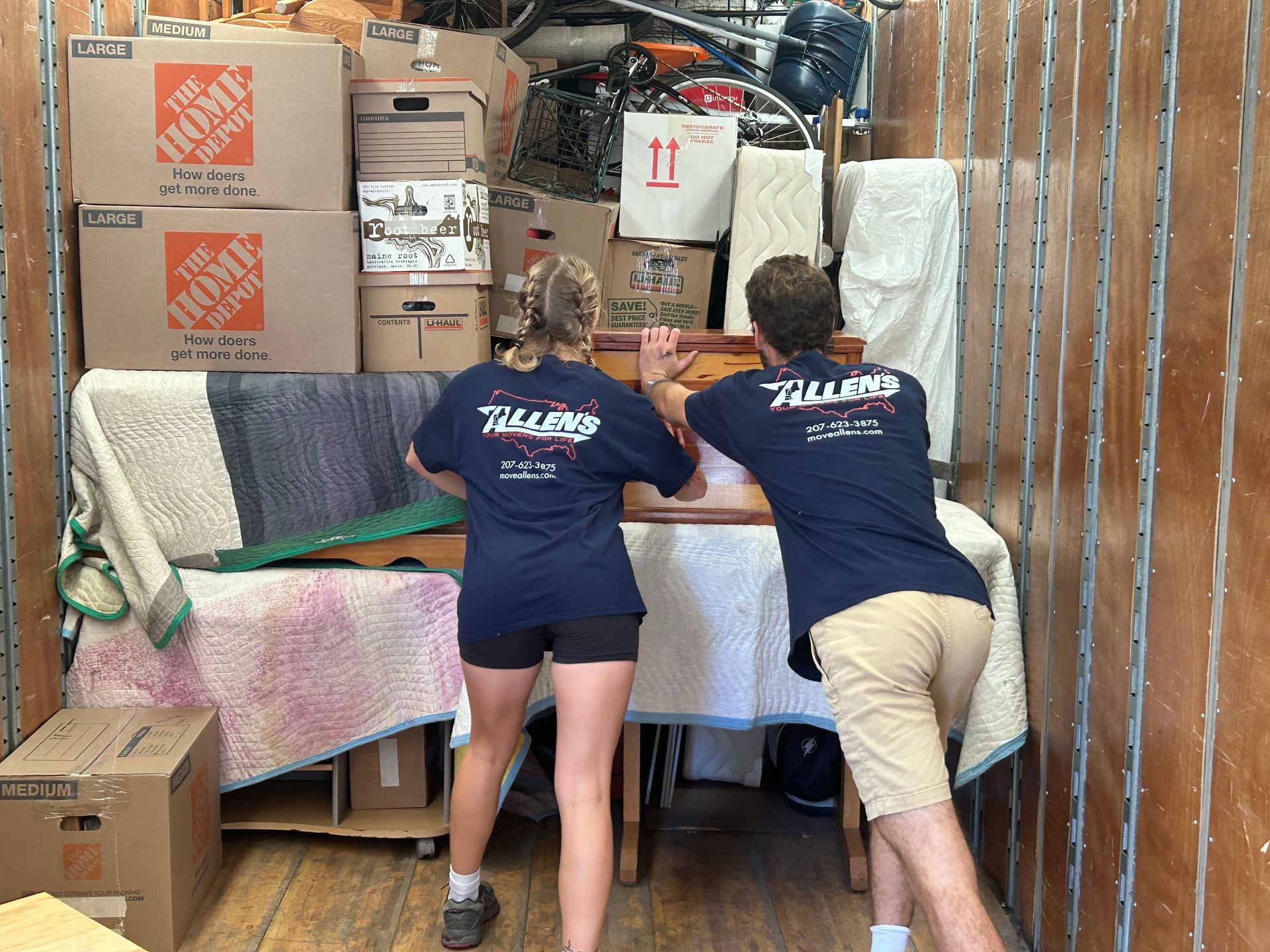 A man and a woman are moving a table in a home depot truck