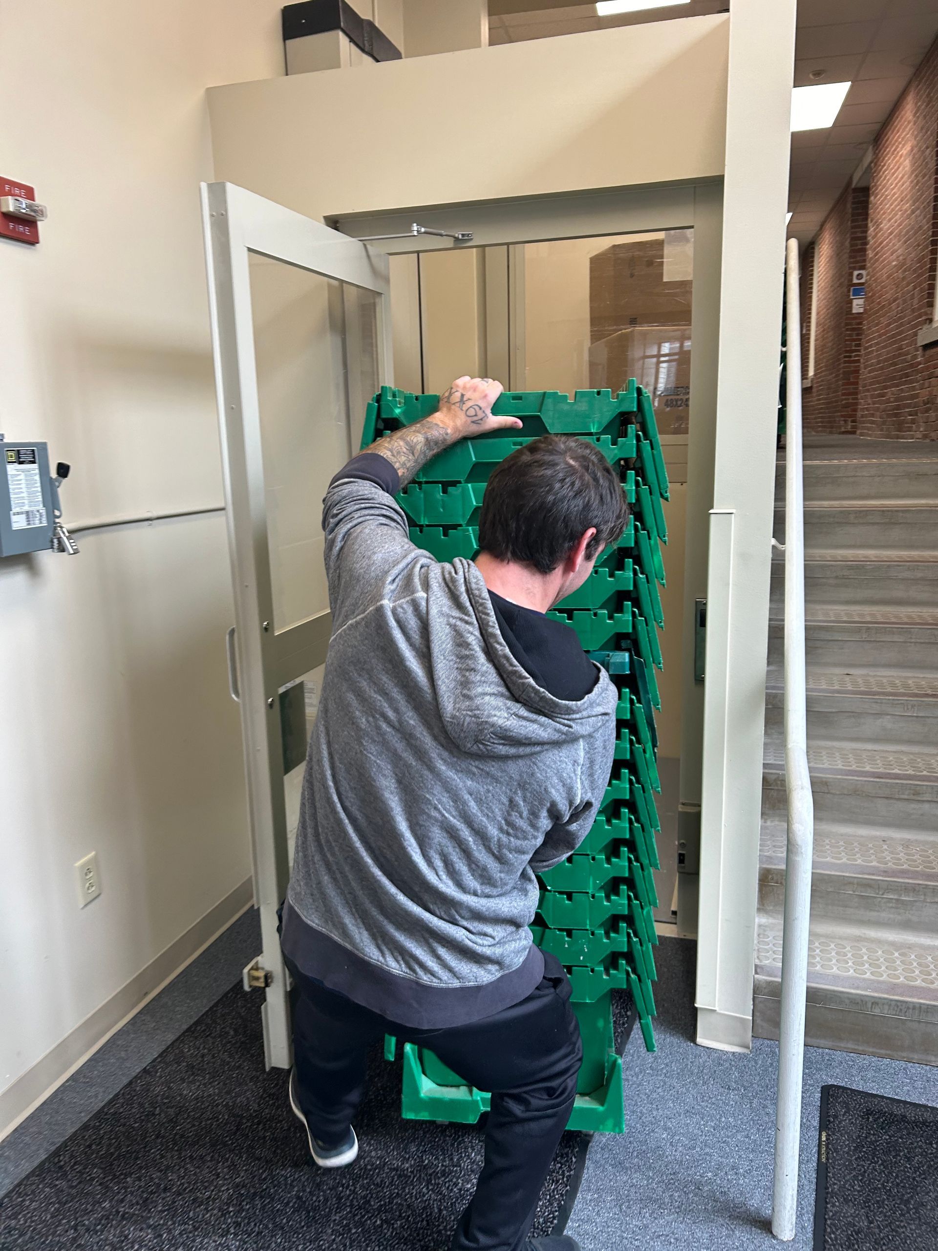 A man is kneeling down in front of a stack of green crates.