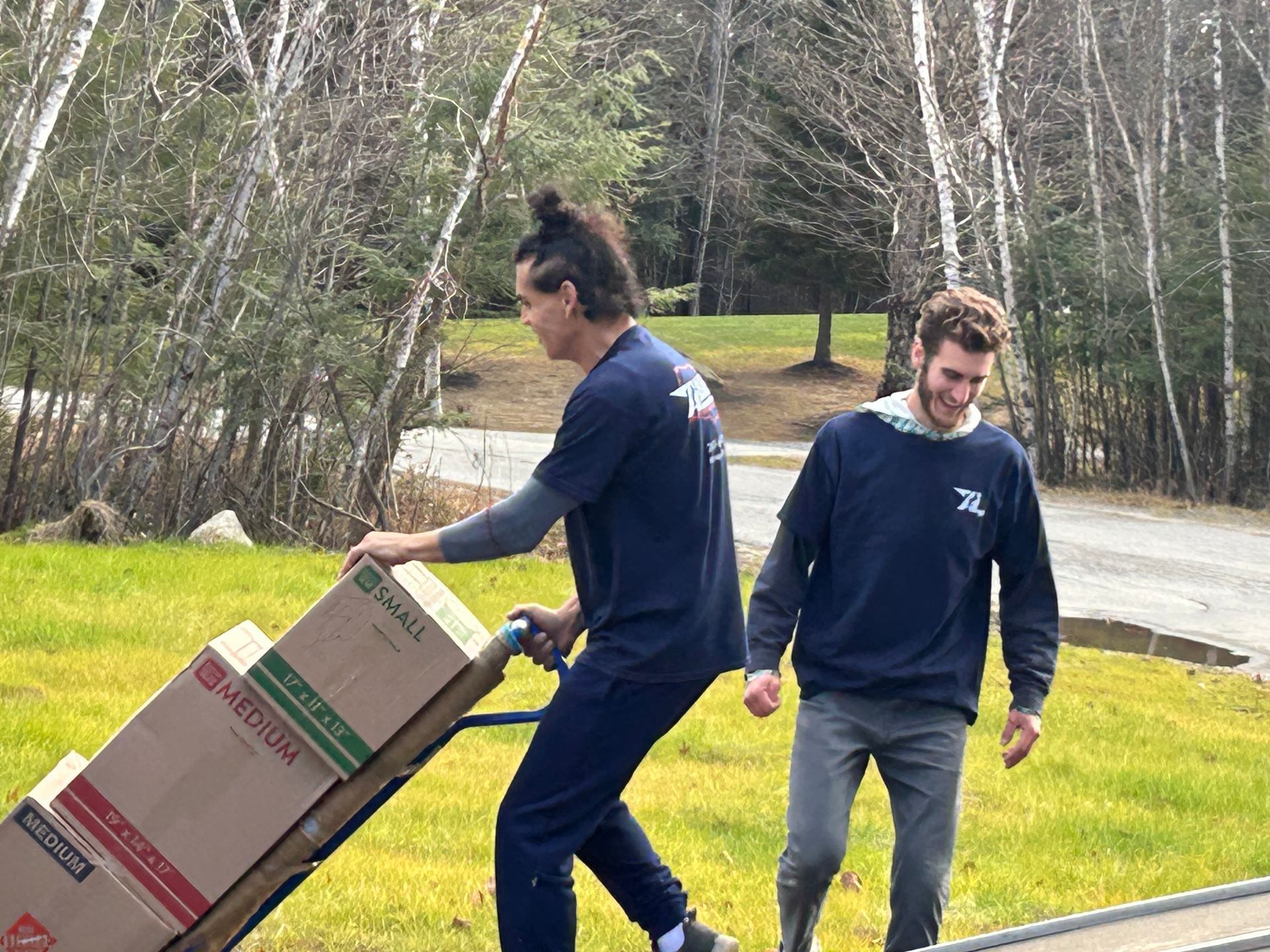 Two men are pushing a cart with boxes on it.