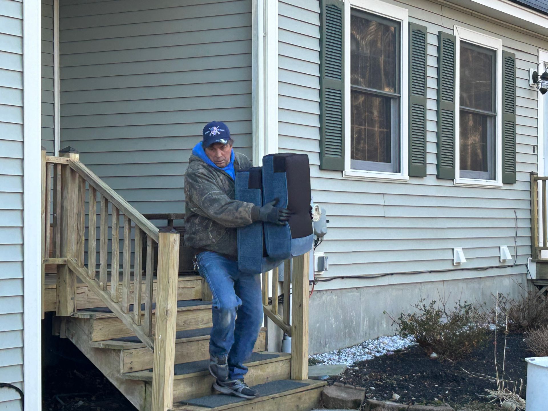 A man is carrying a couch up the stairs of a house.