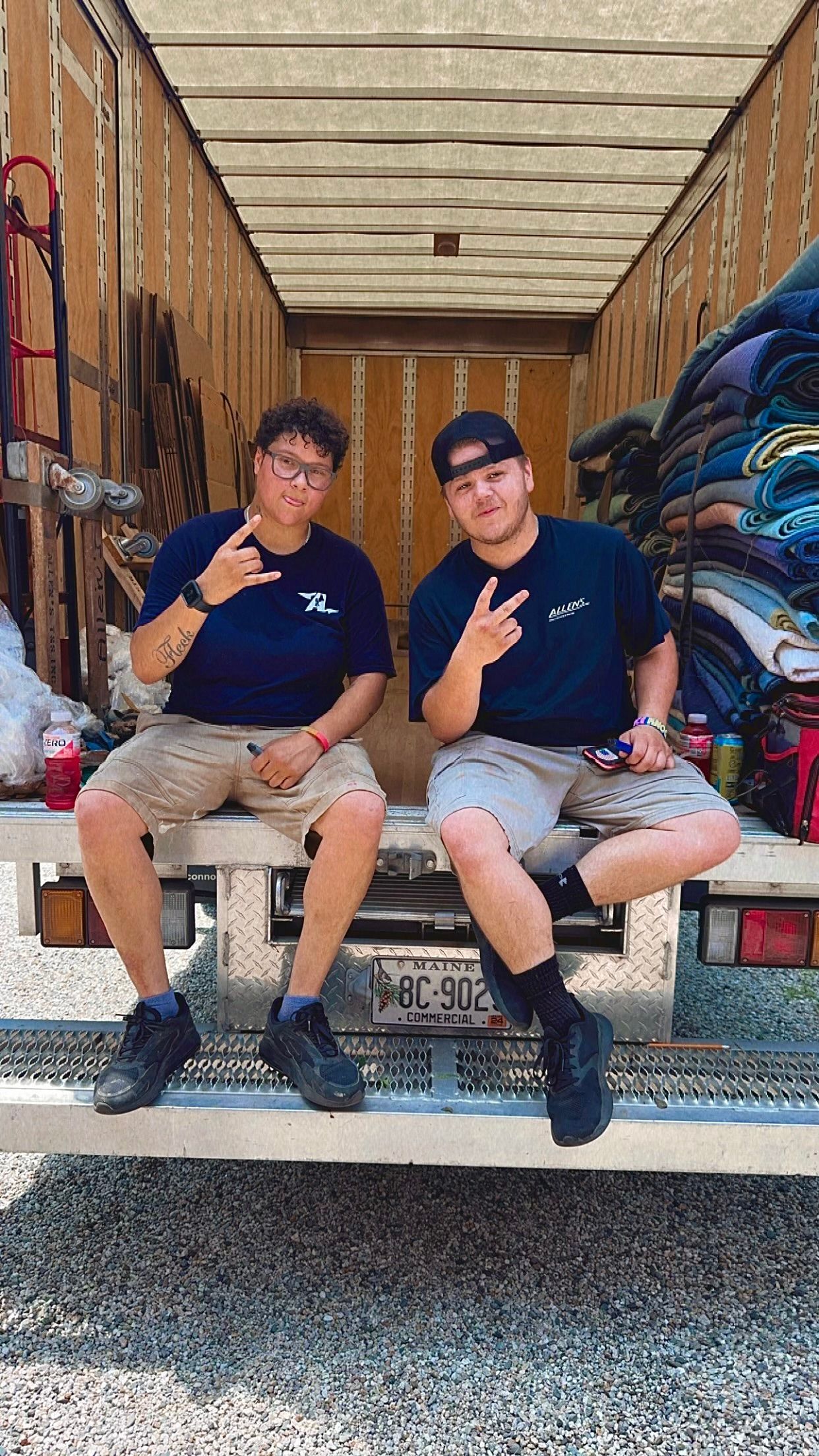Two men are sitting on the back of a truck.