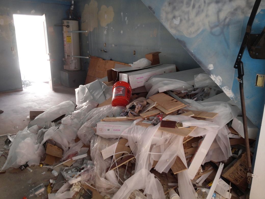 Woman in straw hat smiles, holding wine glass near a lake.