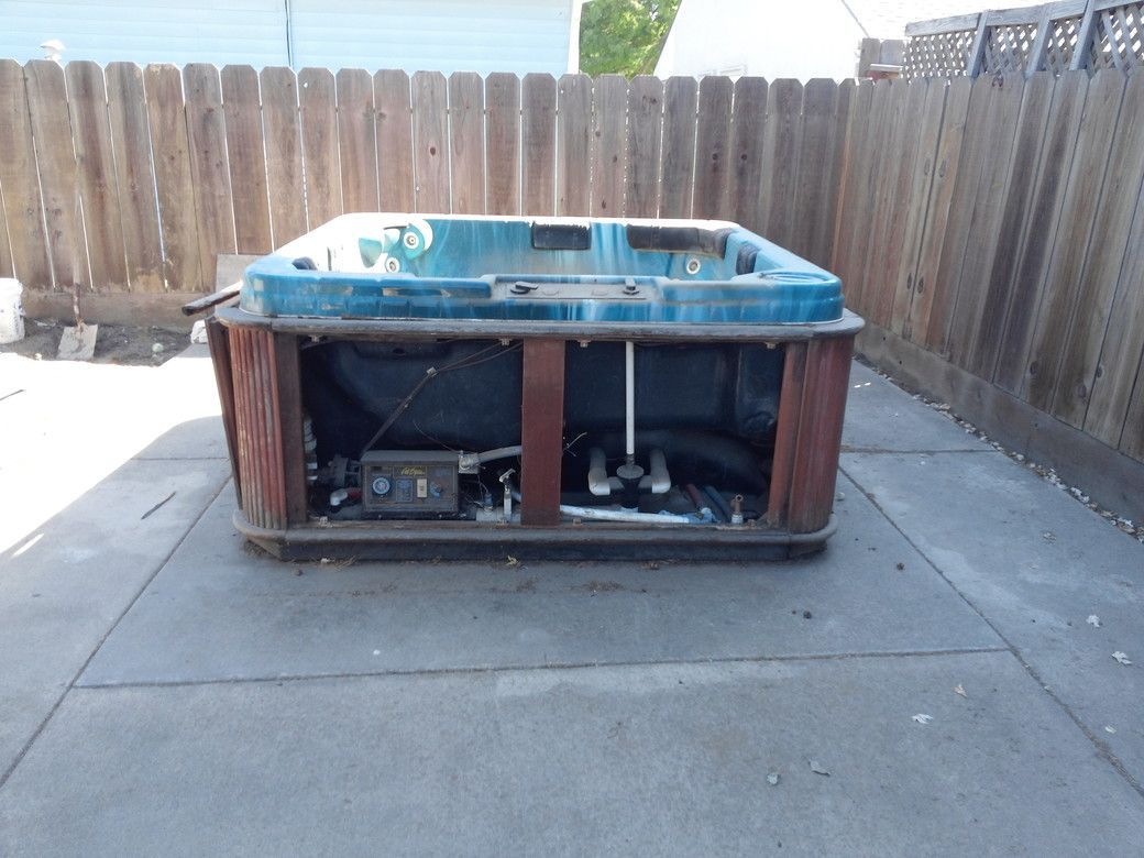 Woman in straw hat smiles, holding wine glass near a lake.