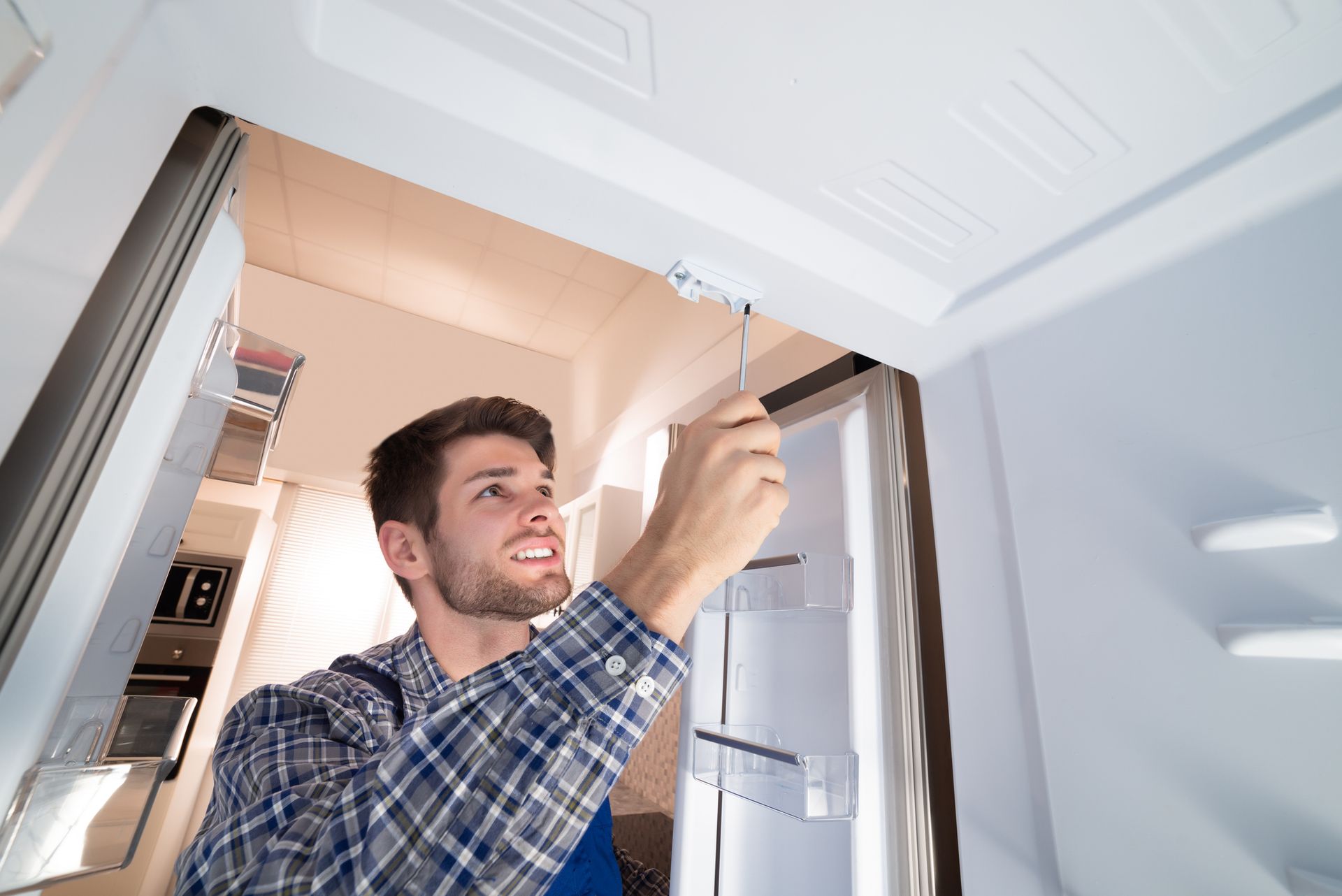 A male technician checking a refrigerator. A male technician checking a refrigerator.