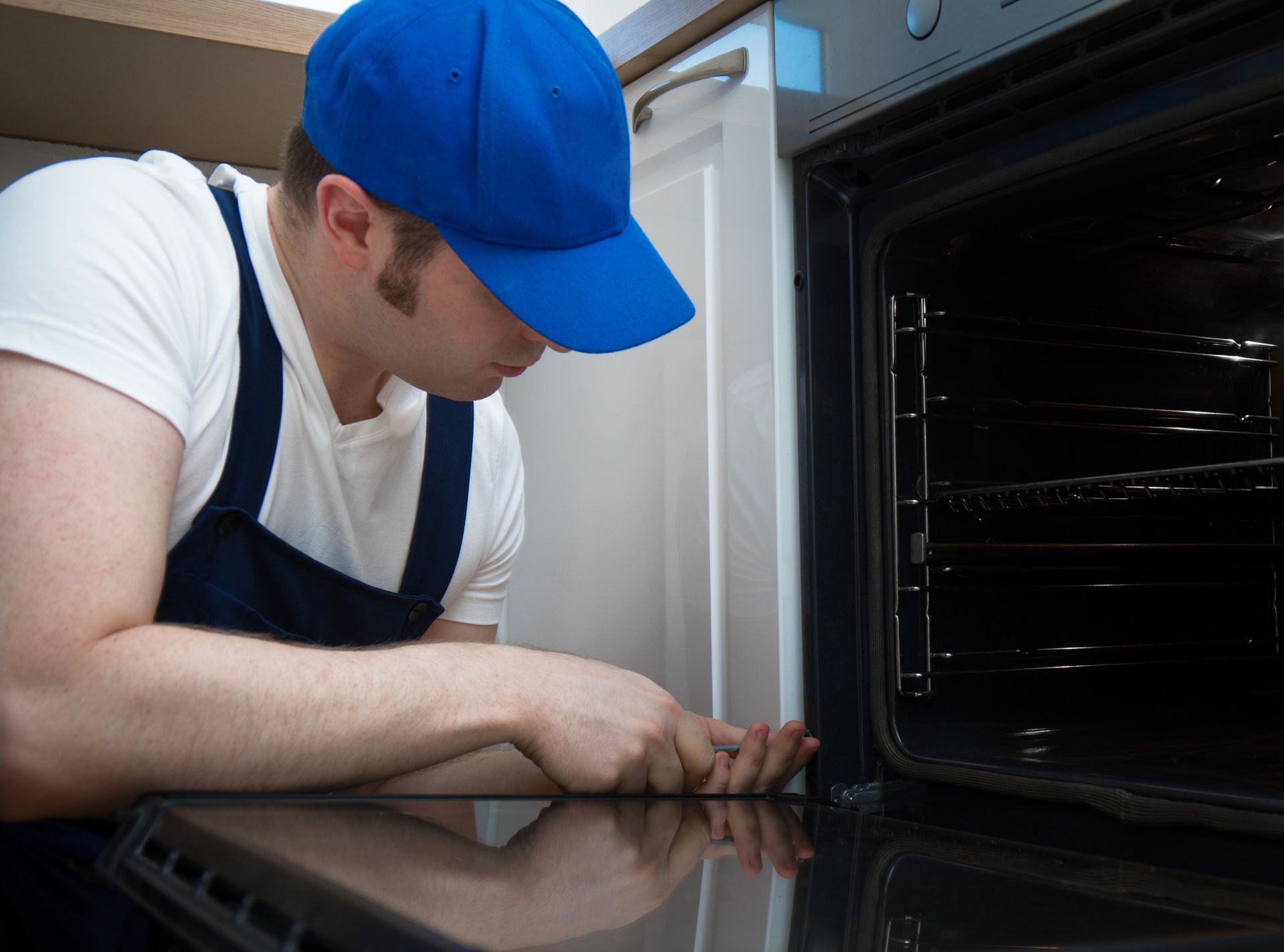 Handyman fixing oven, showcasing expert appliance repair skills inside a modern kitchen.