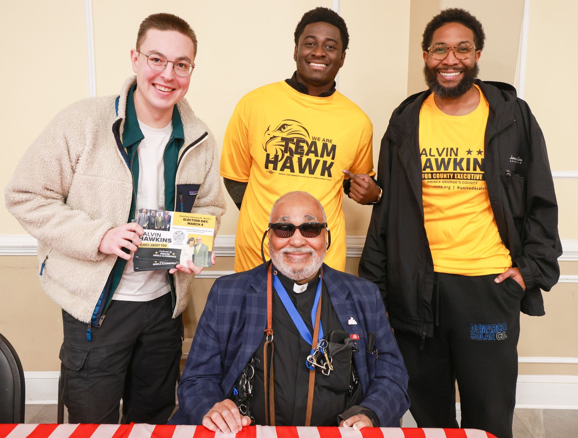 A group of men are posing for a picture and one of them is wearing a shirt that says team hawk