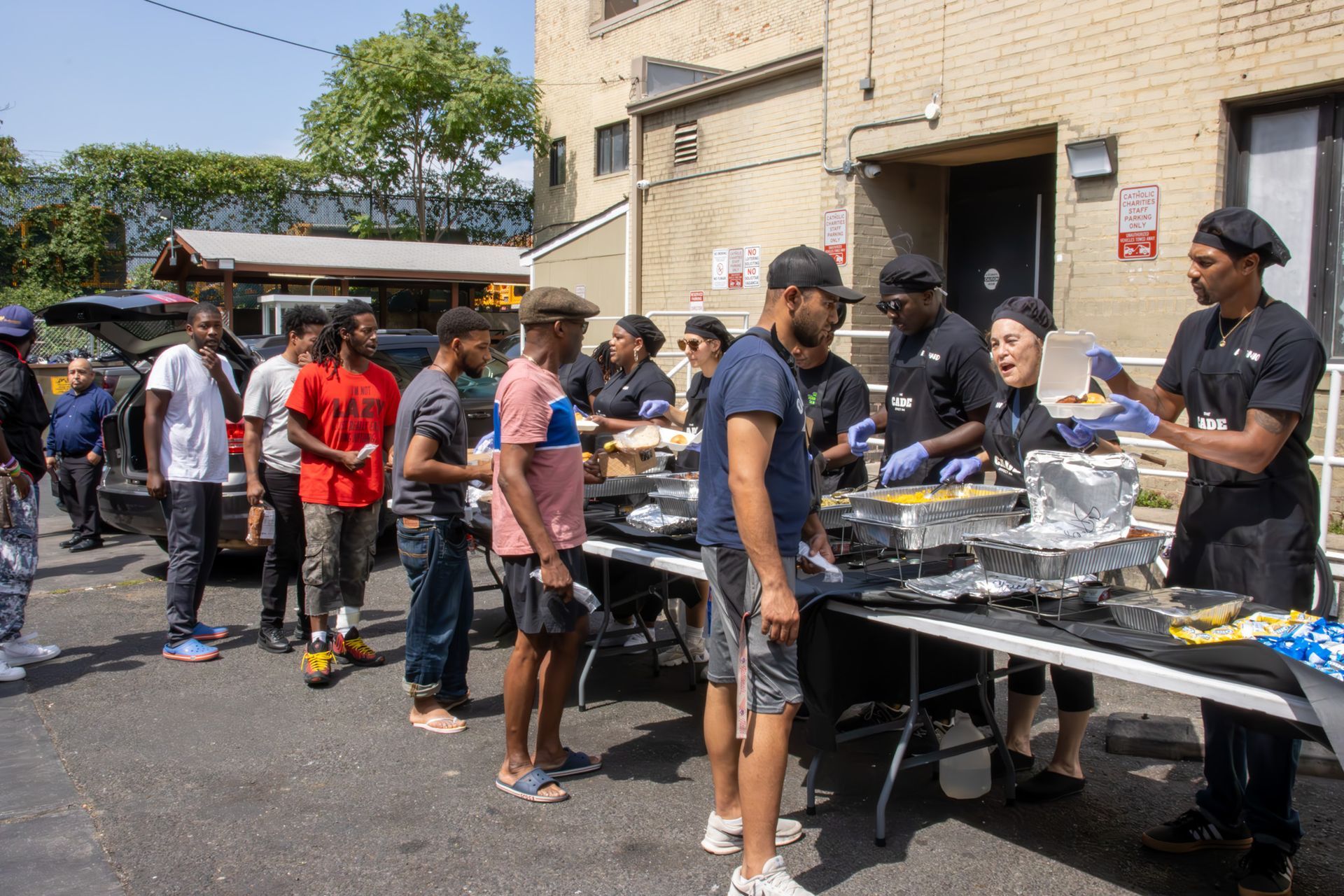 A group of people are standing in line to get food from a table.