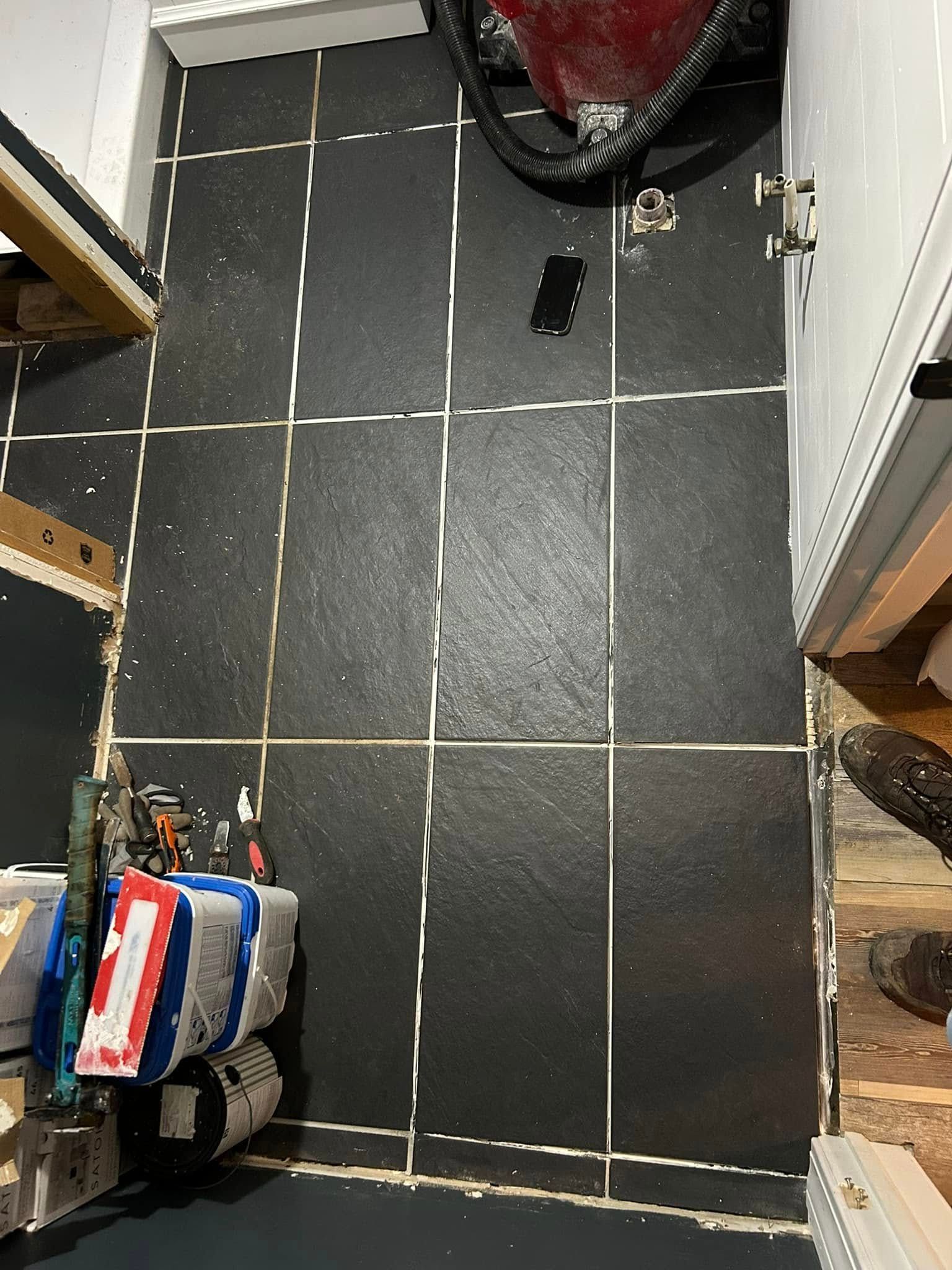 Black tiled floor with white grout, tools scattered, and storage.